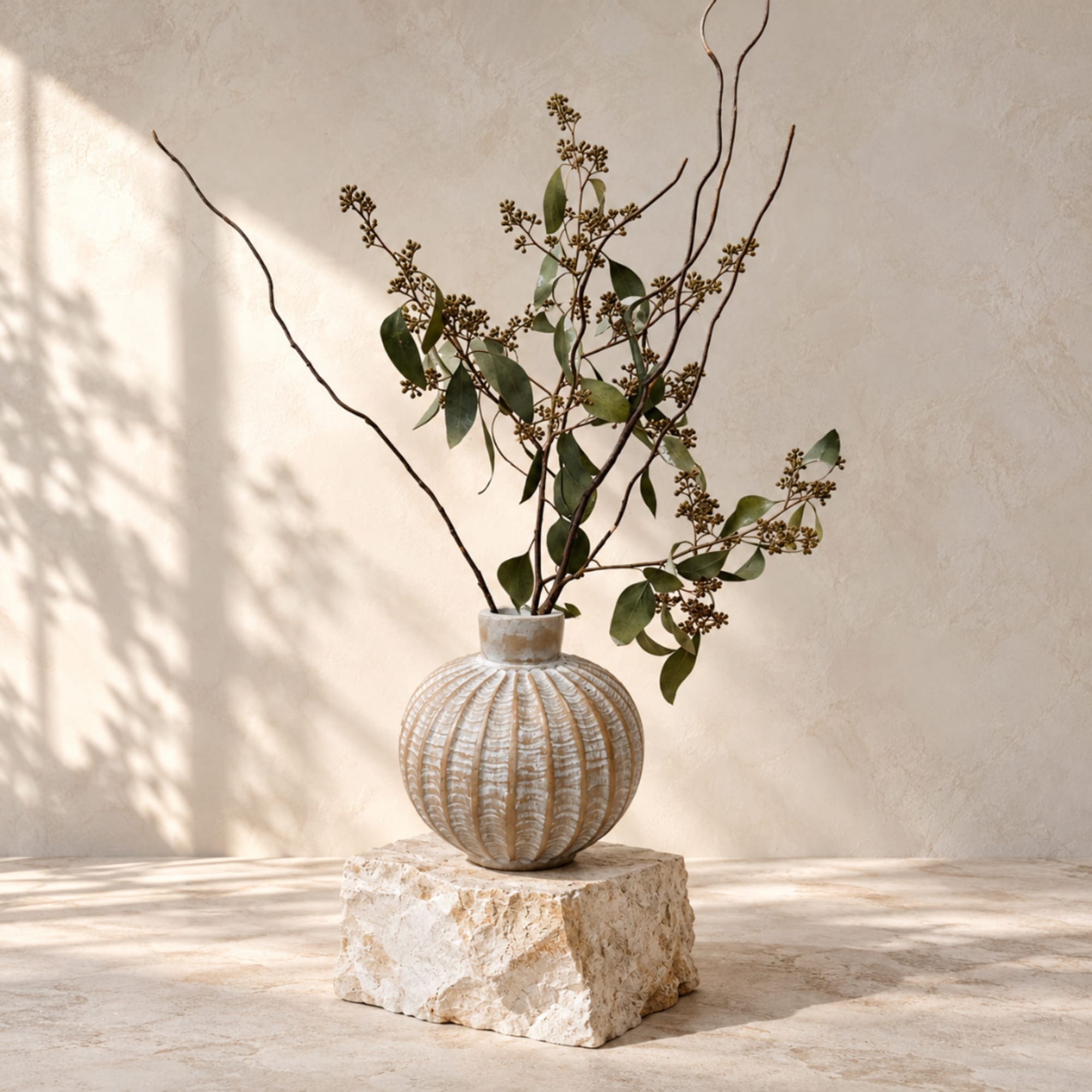 Branch arrangement in a textured round vase on a stone block