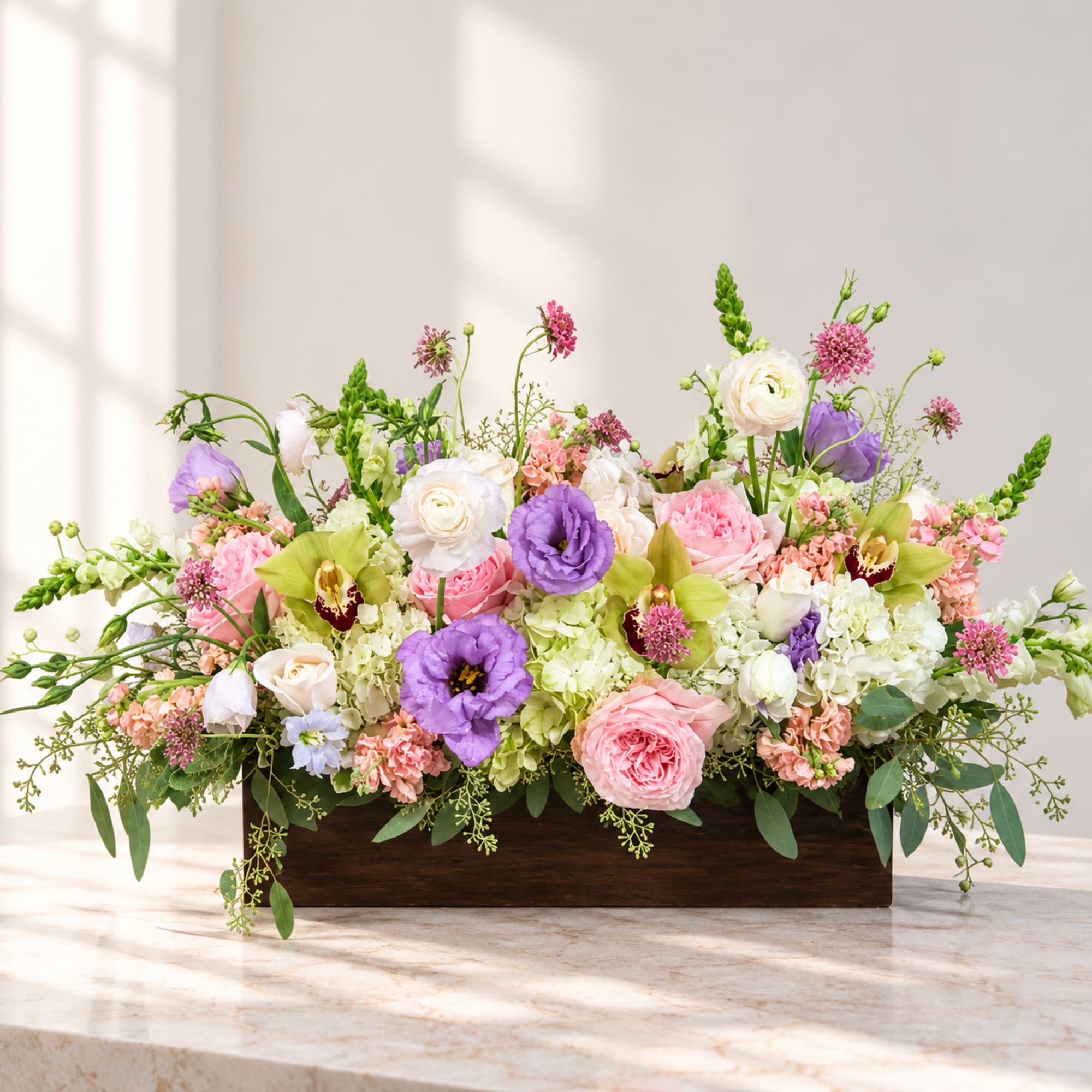 Mixed pink, white, purple, and green floral arrangement in a wooden box