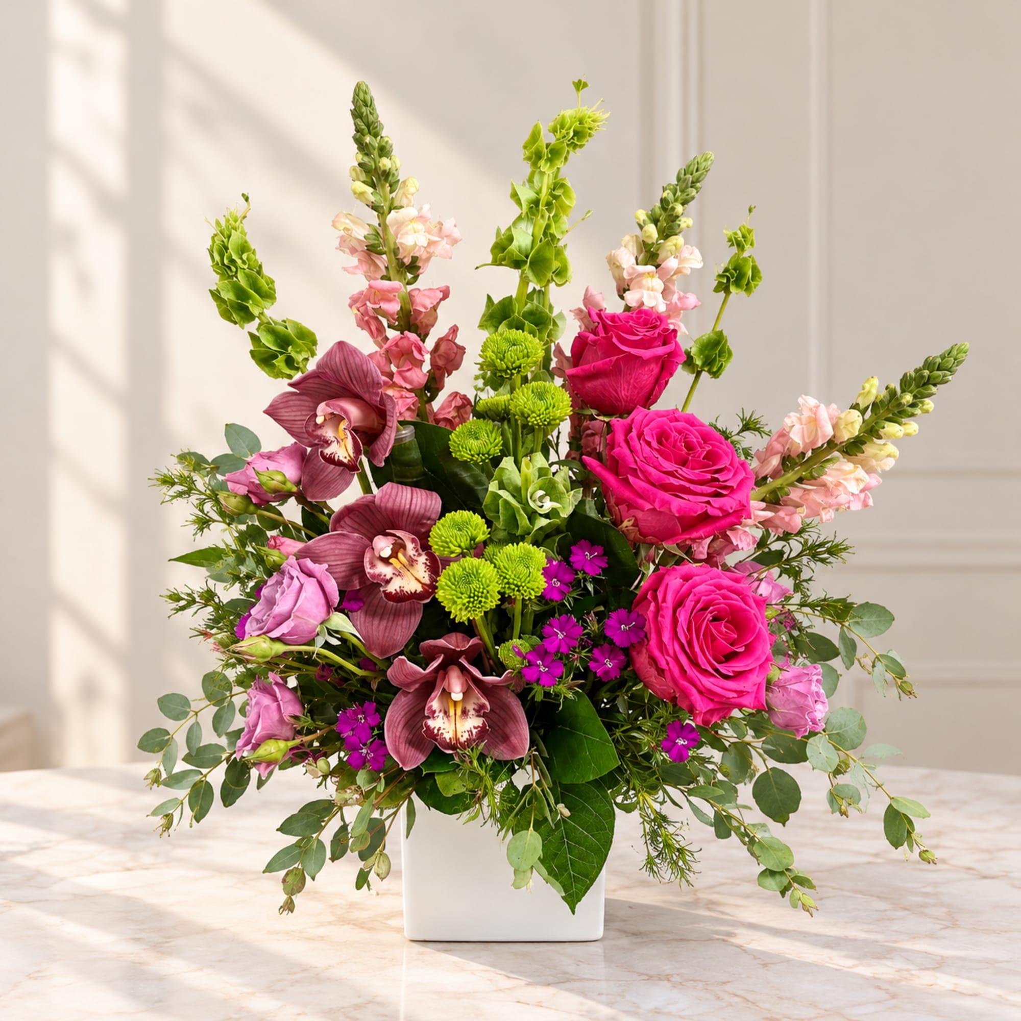 Pink roses and orchids in a white square vase