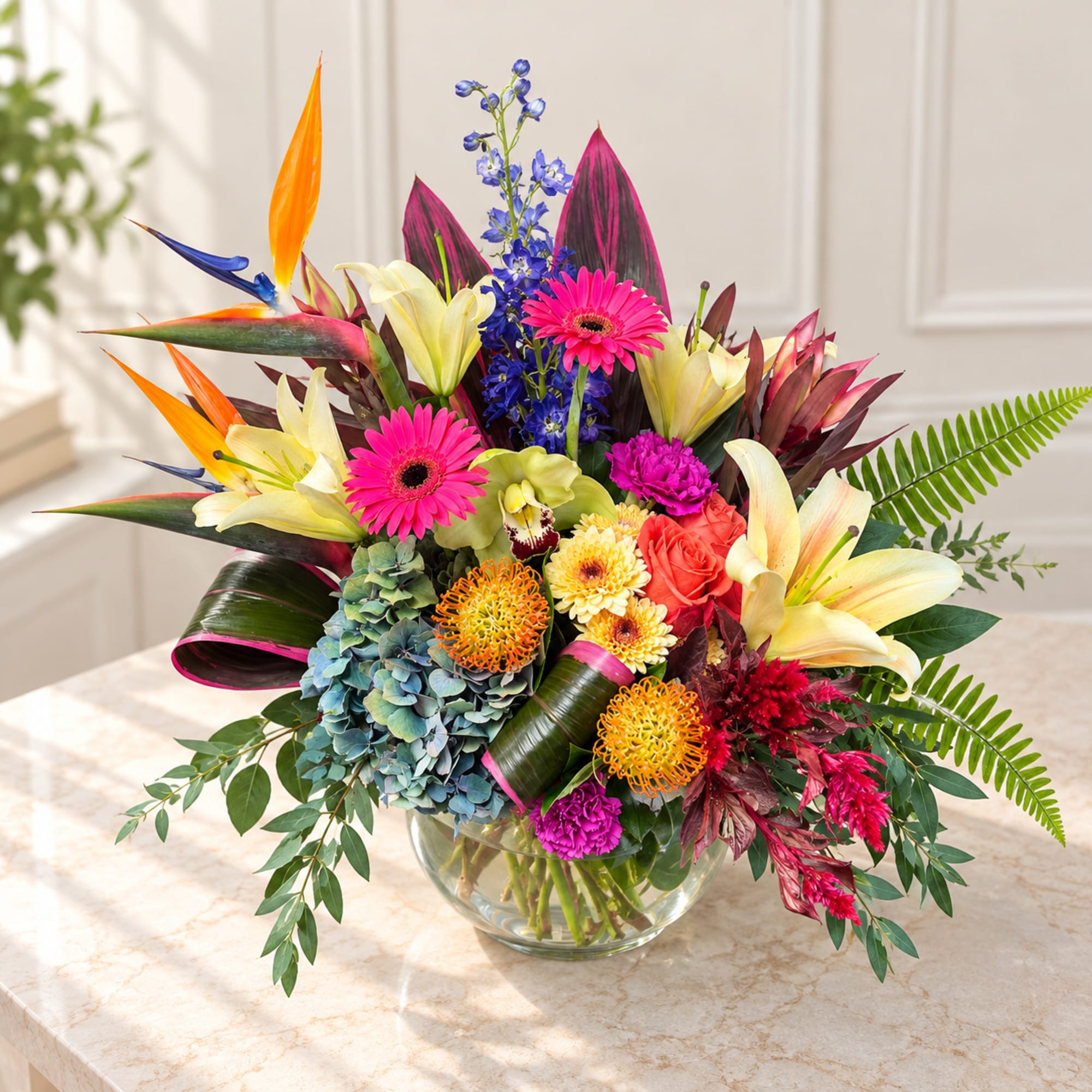 Colorful tropical bouquet in a clear glass bowl vase