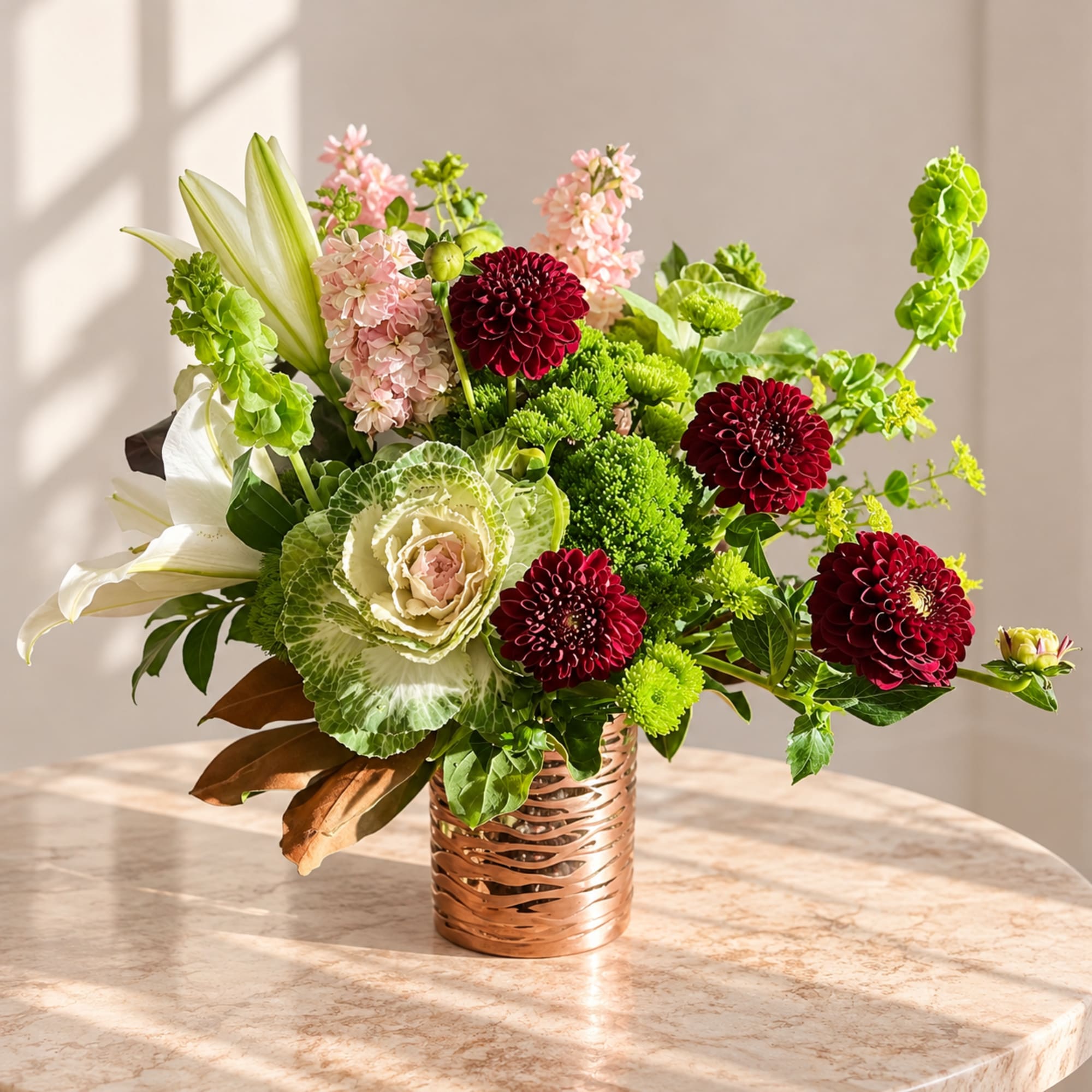 Mixed floral arrangement in a copper vase with white lilies and burgundy blooms