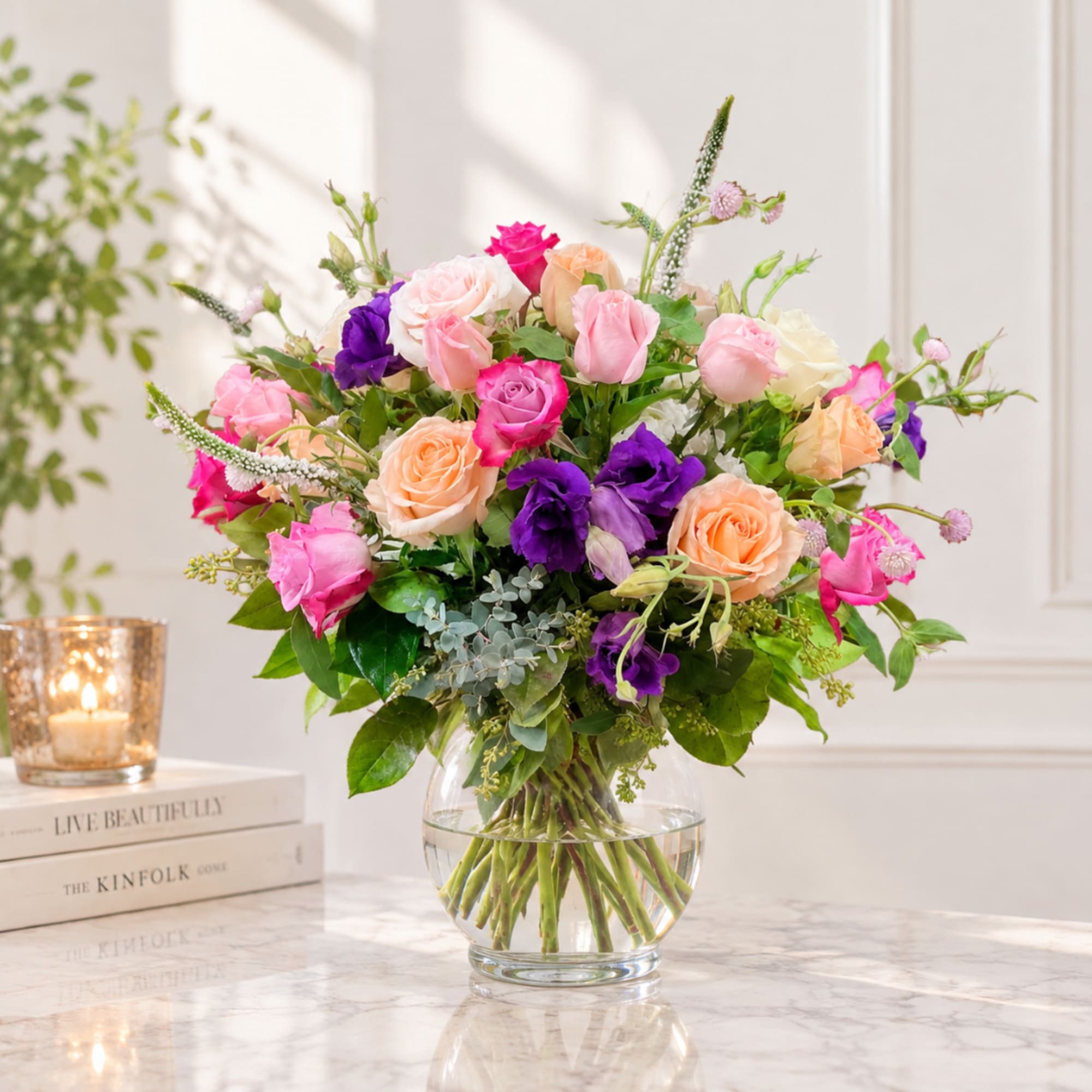 Mixed bouquet of pink, peach, purple, and white flowers in a glass vase