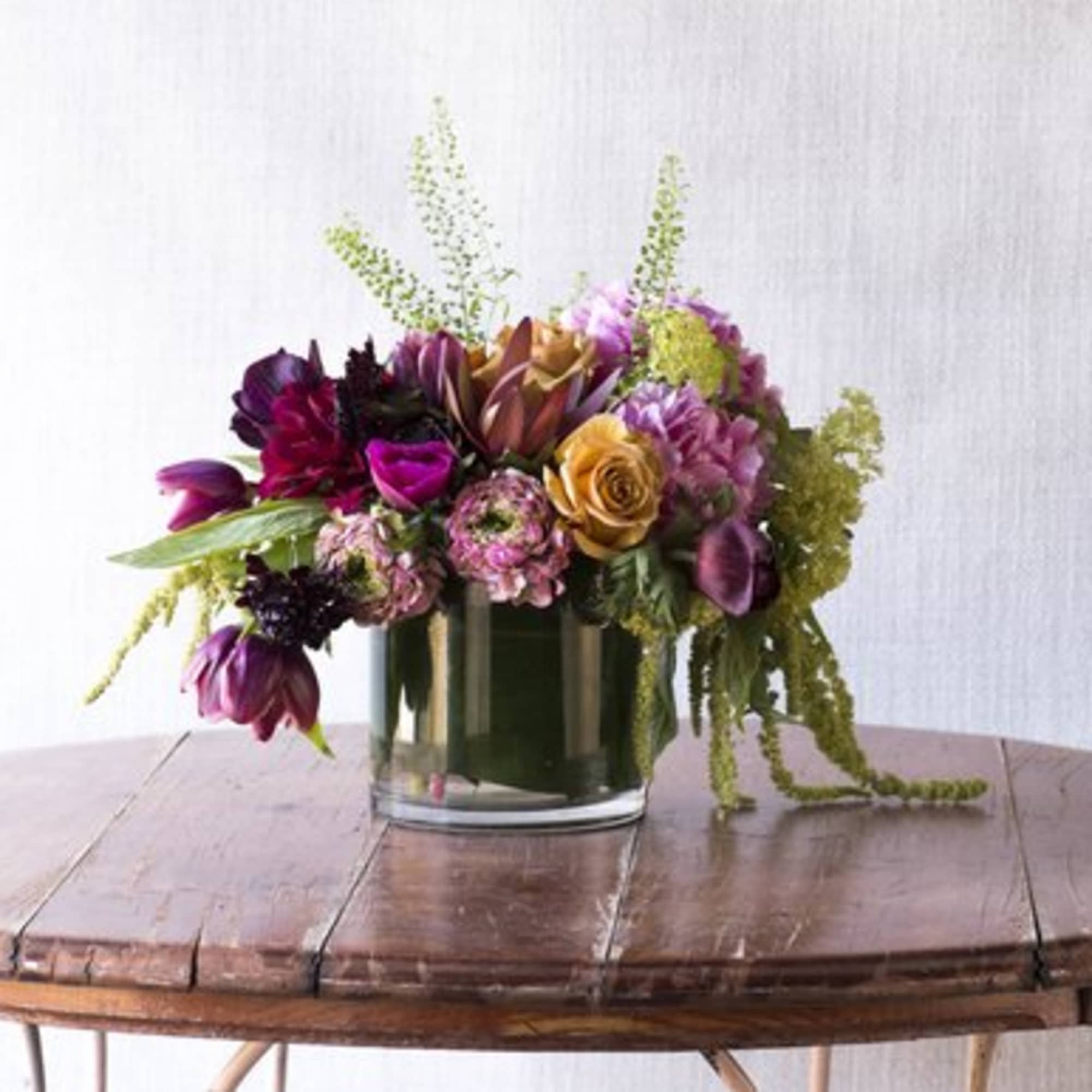 Mixed bouquet in a clear glass vase with purple, pink, and gold blooms