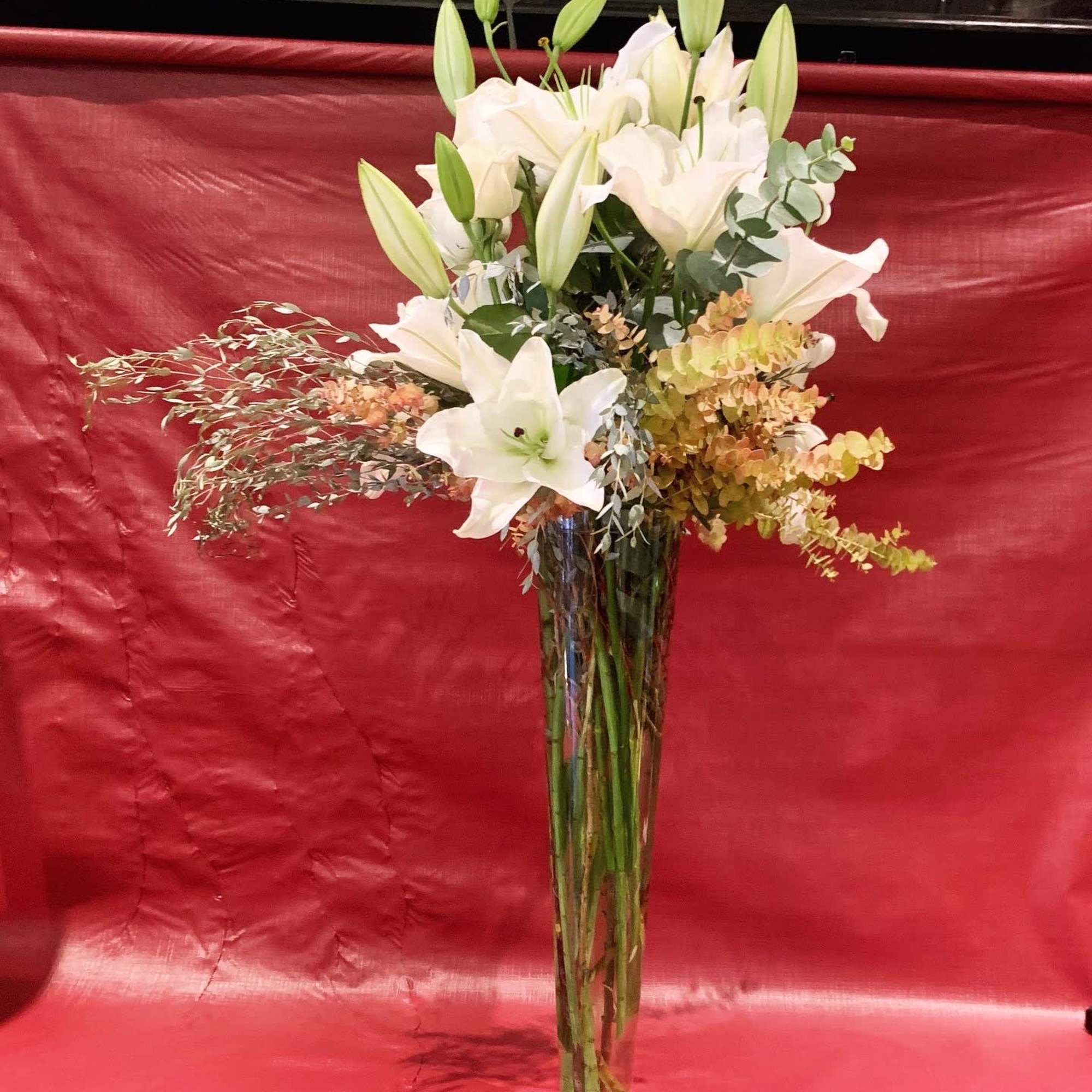 Tall white lily arrangement in a clear glass vase
