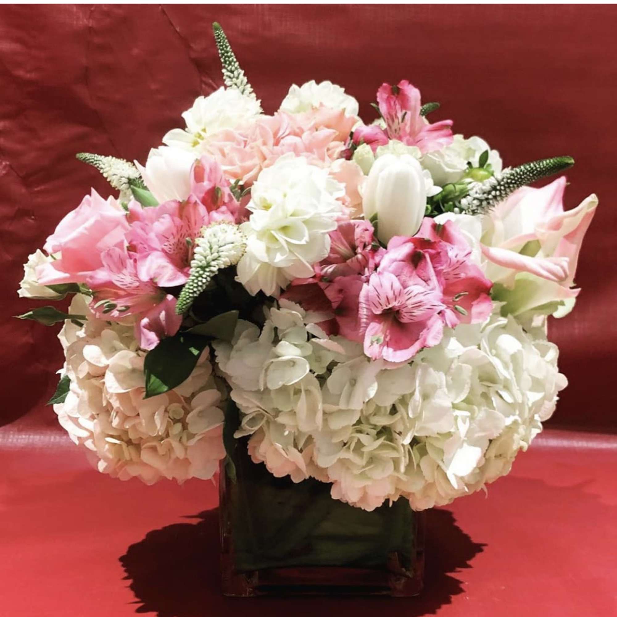 Pink and white floral arrangement in a dark vase