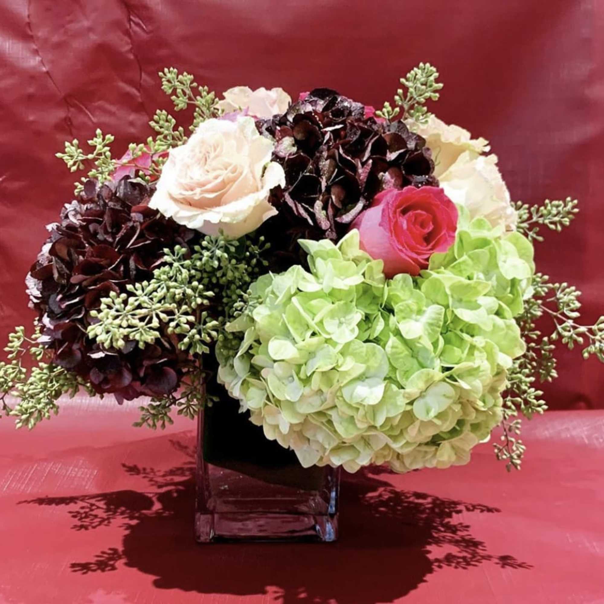 Bouquet of hydrangeas and roses in a square glass vase