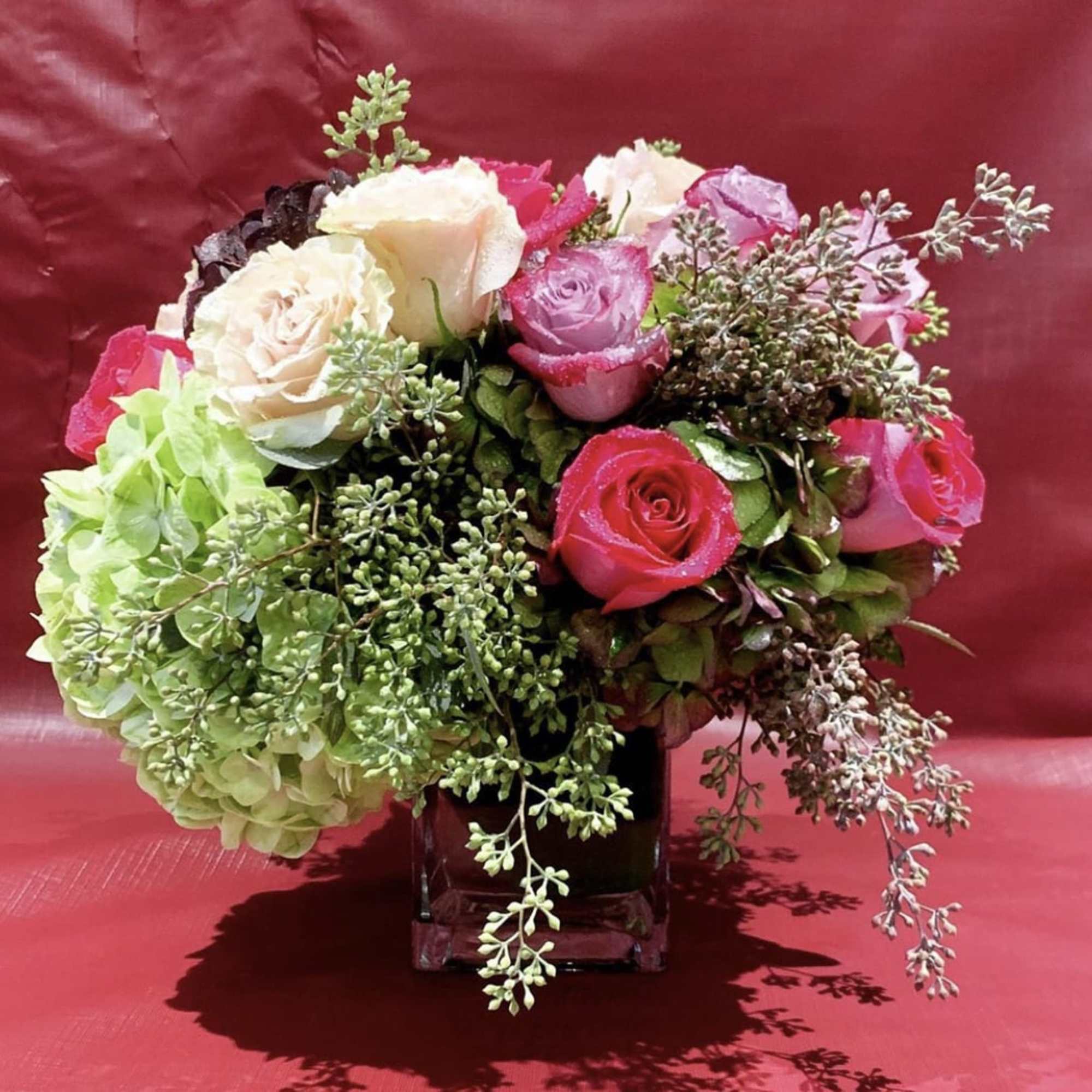Bouquet of pink and cream roses with green hydrangea in a glass vase