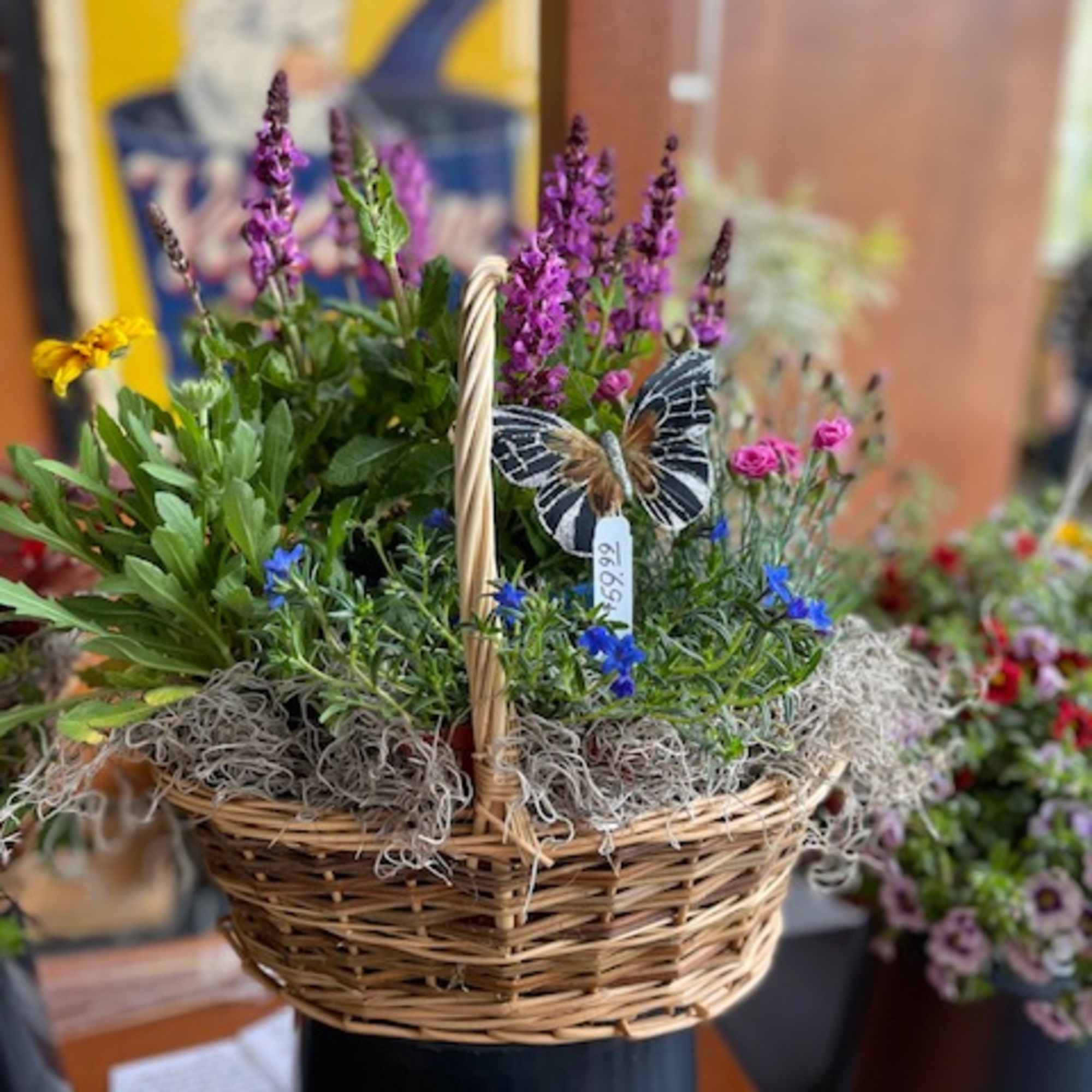 Basket of purple and blue flowers with a butterfly decoration
