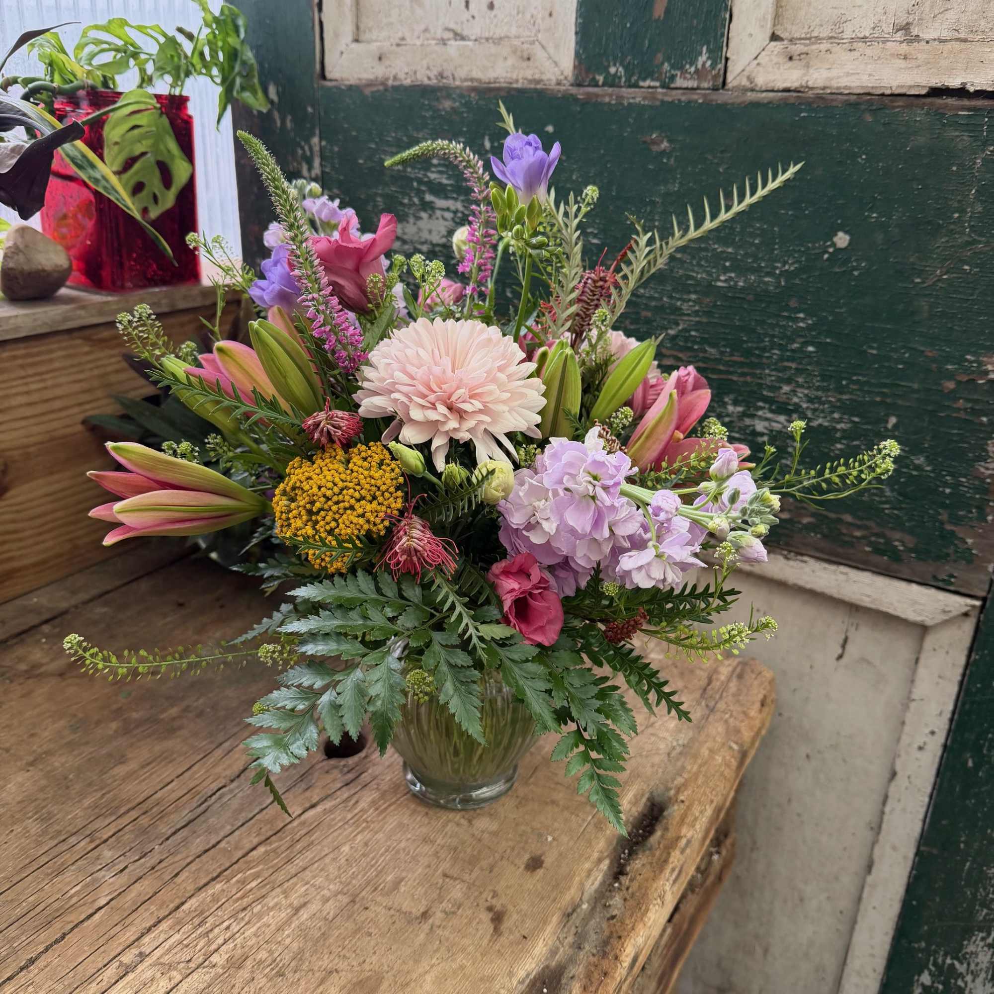 Mixed bouquet in a clear glass vase with pink, purple, and yellow blooms