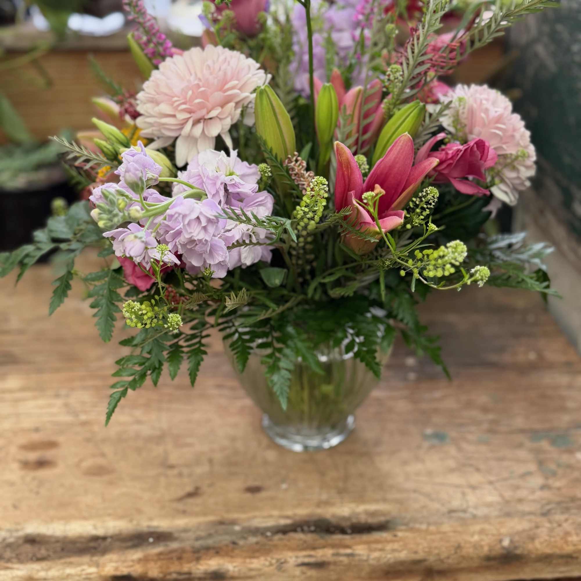 Mixed pink and lavender flowers arranged in a clear glass vase