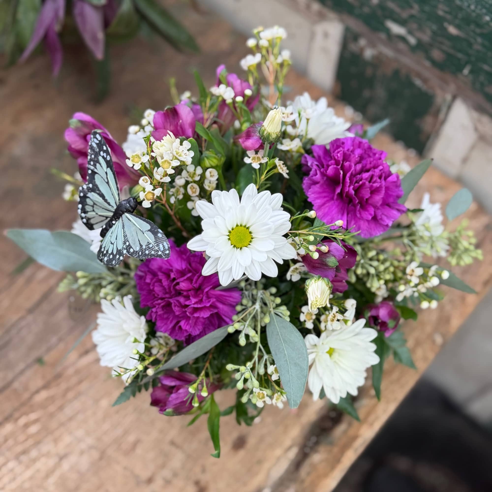Bouquet of white daisies and purple carnations with a butterfly decoration