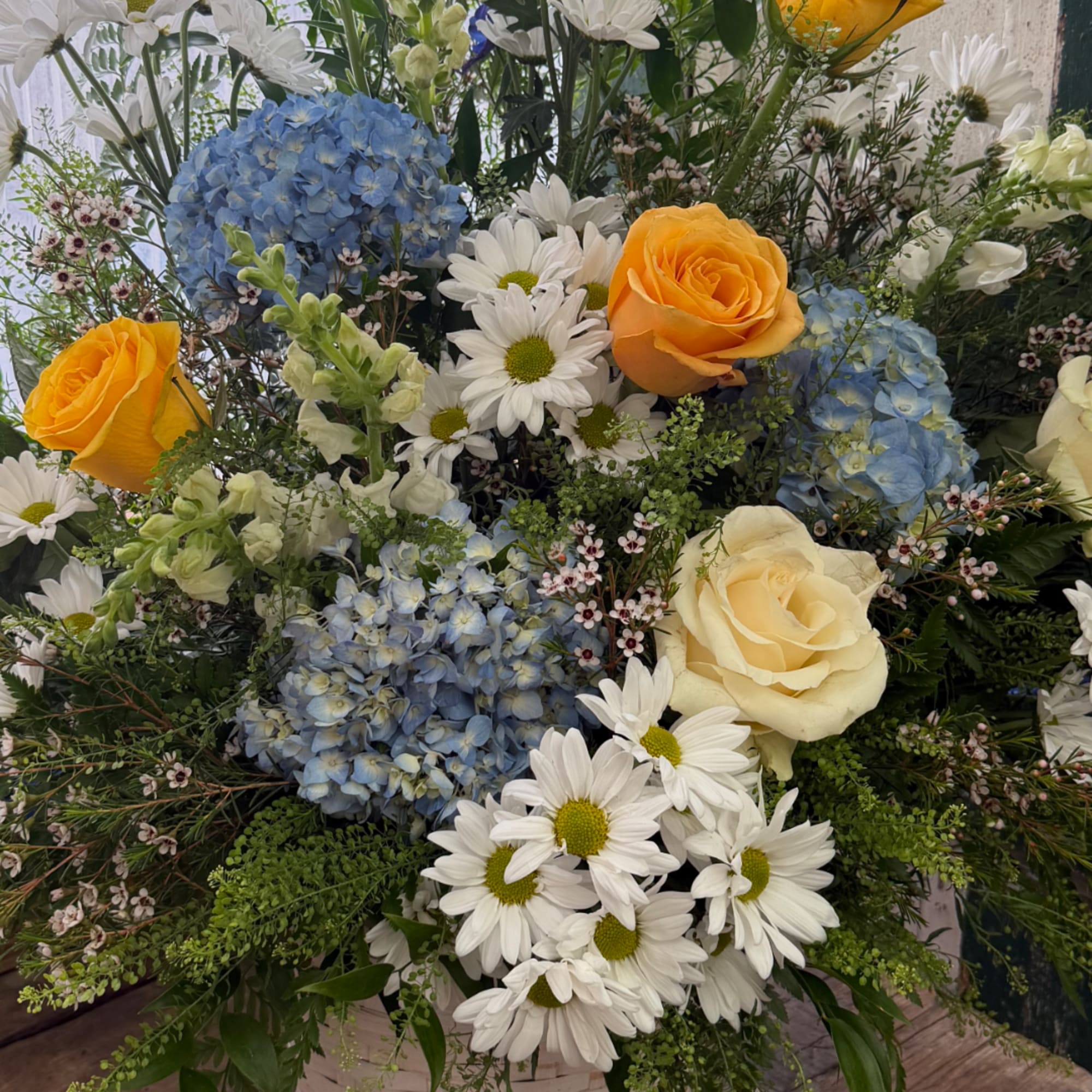Mixed bouquet with blue hydrangeas, white daisies, and yellow roses