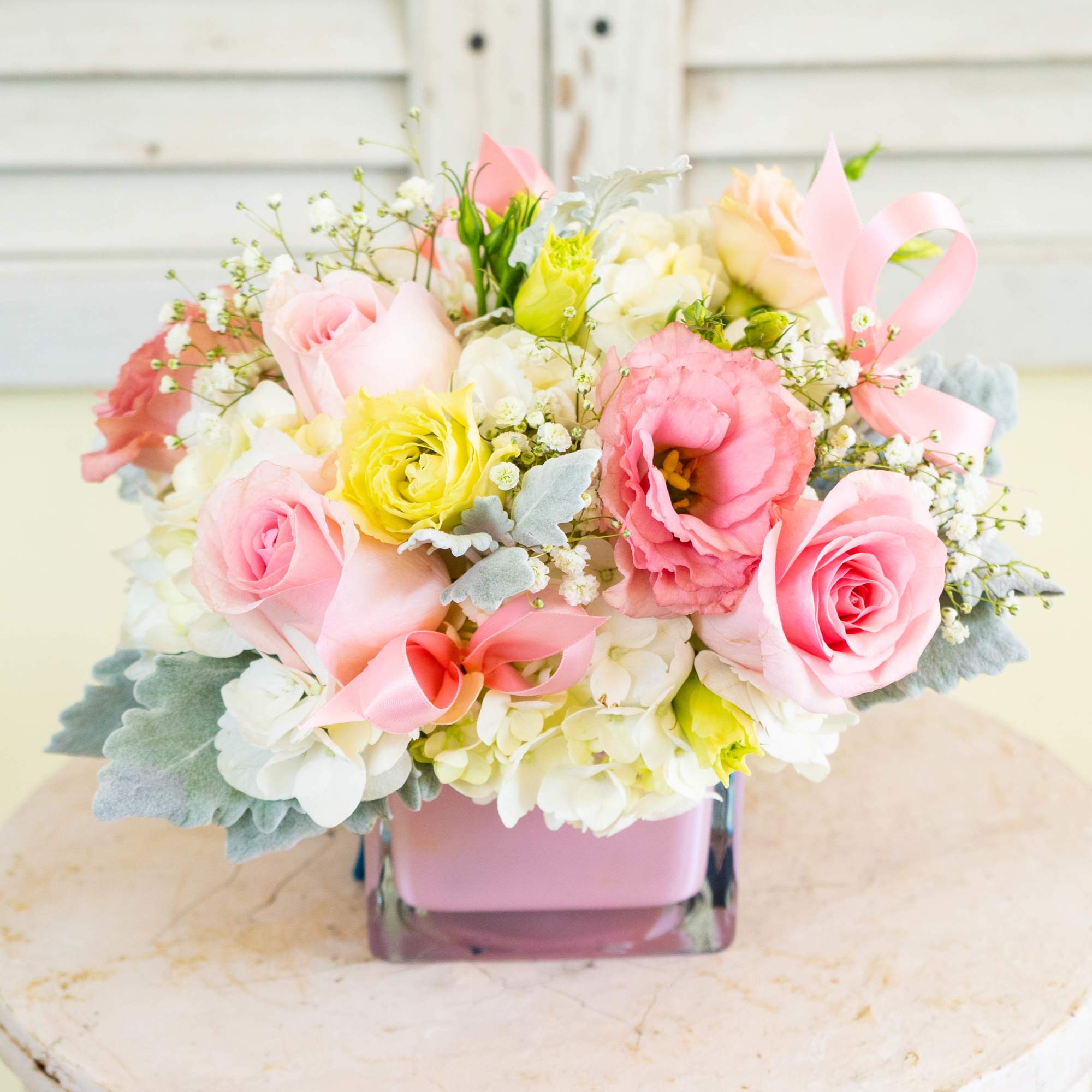 Pink and white bouquet in a square glass vase with ribbon accents