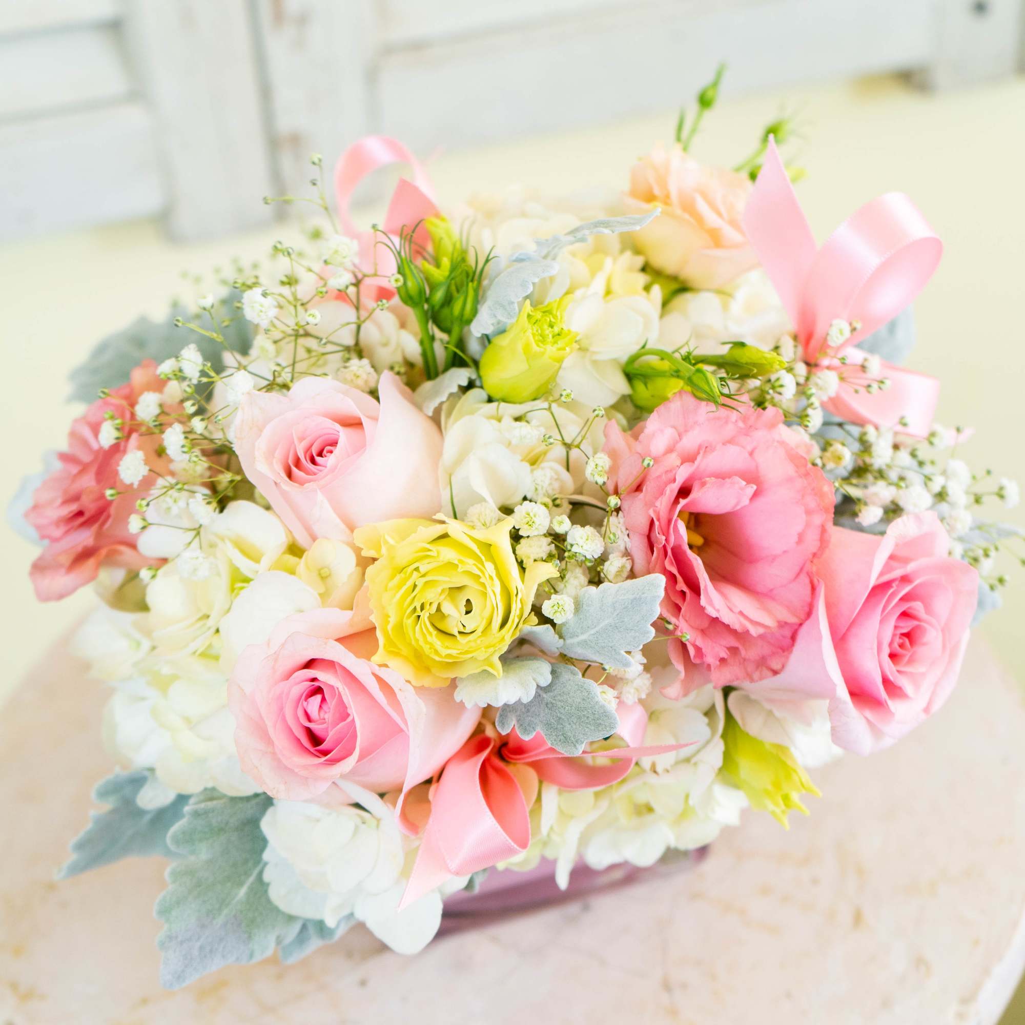 Pink and yellow rose bouquet with white flowers and ribbon accents