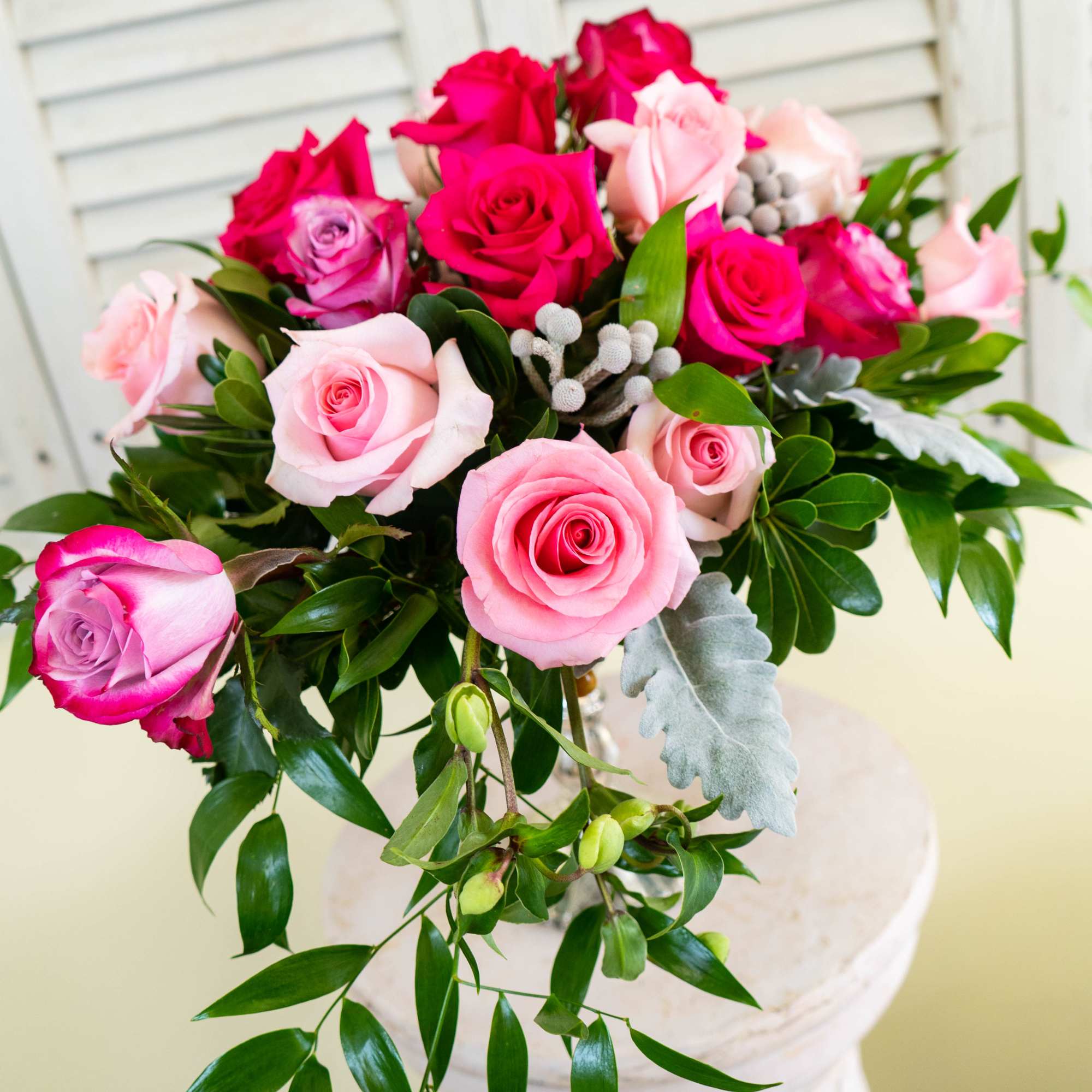 Bouquet of pink and hot pink roses with greenery in a vase