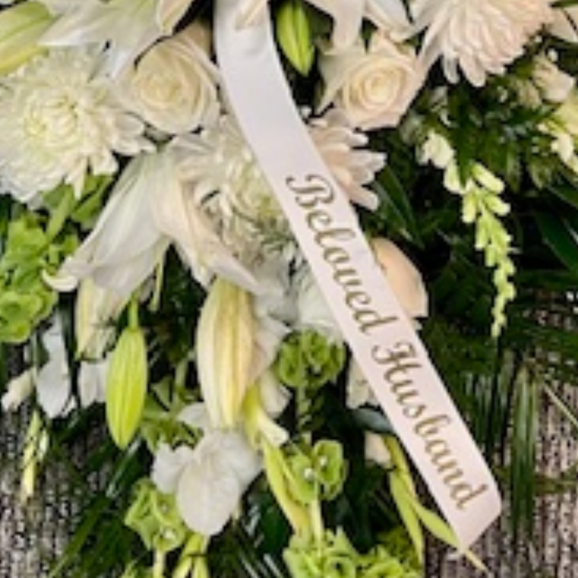 White floral funeral spray with a memorial ribbon