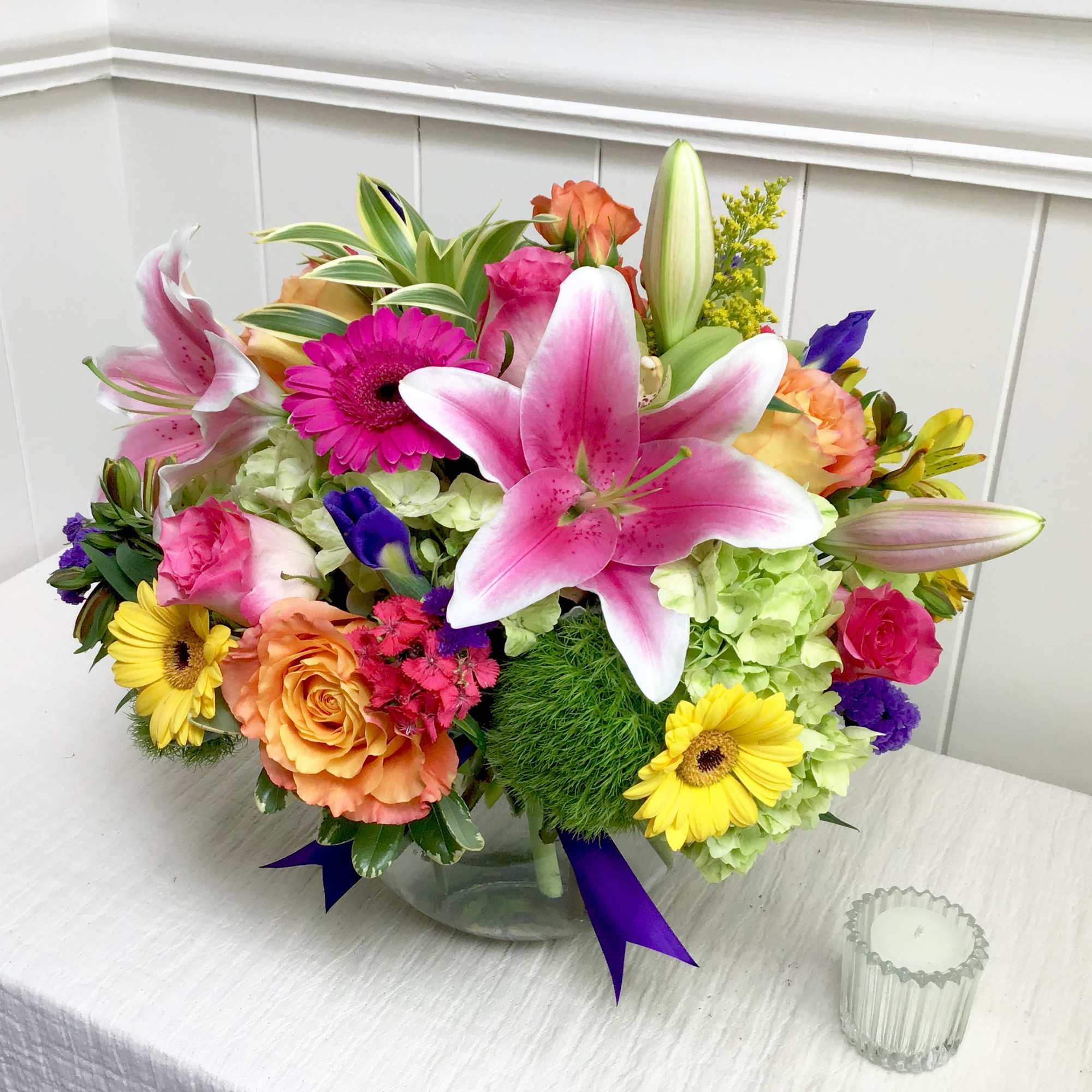 Mixed bouquet in a clear glass vase with pink lilies, roses, and gerbera daisies