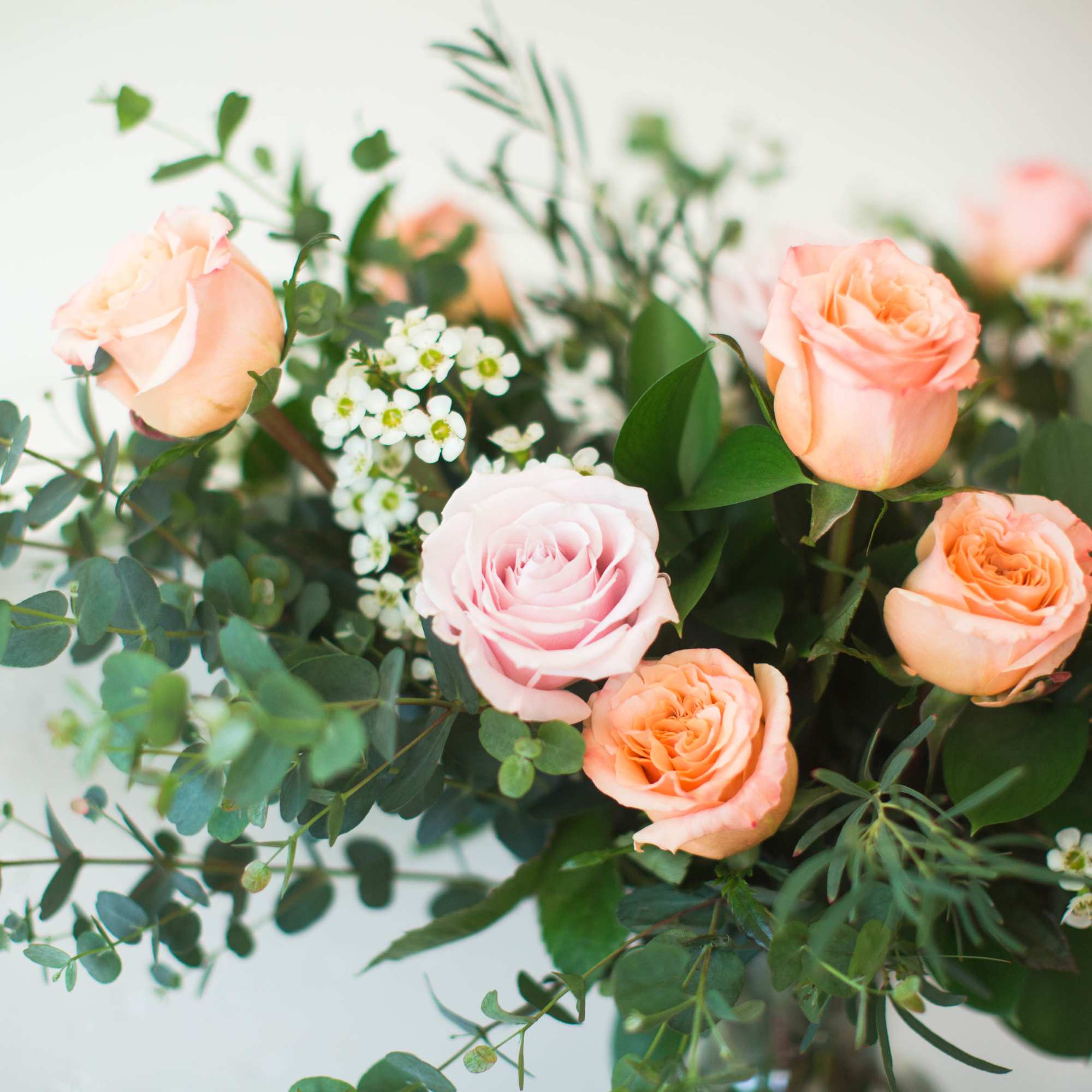 Peach and pale pink roses with white filler flowers and greenery