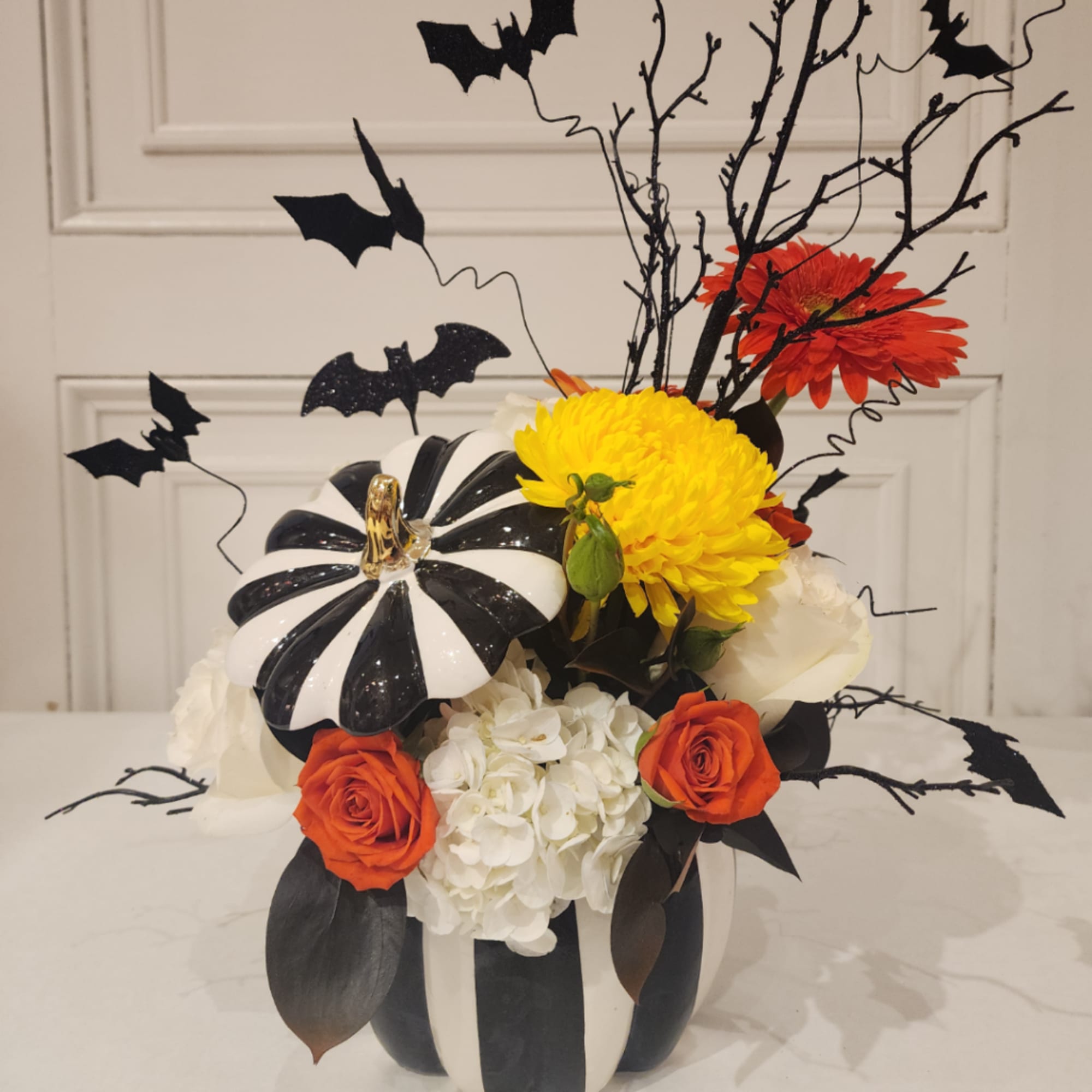 Halloween floral arrangement in a striped pumpkin container with bats