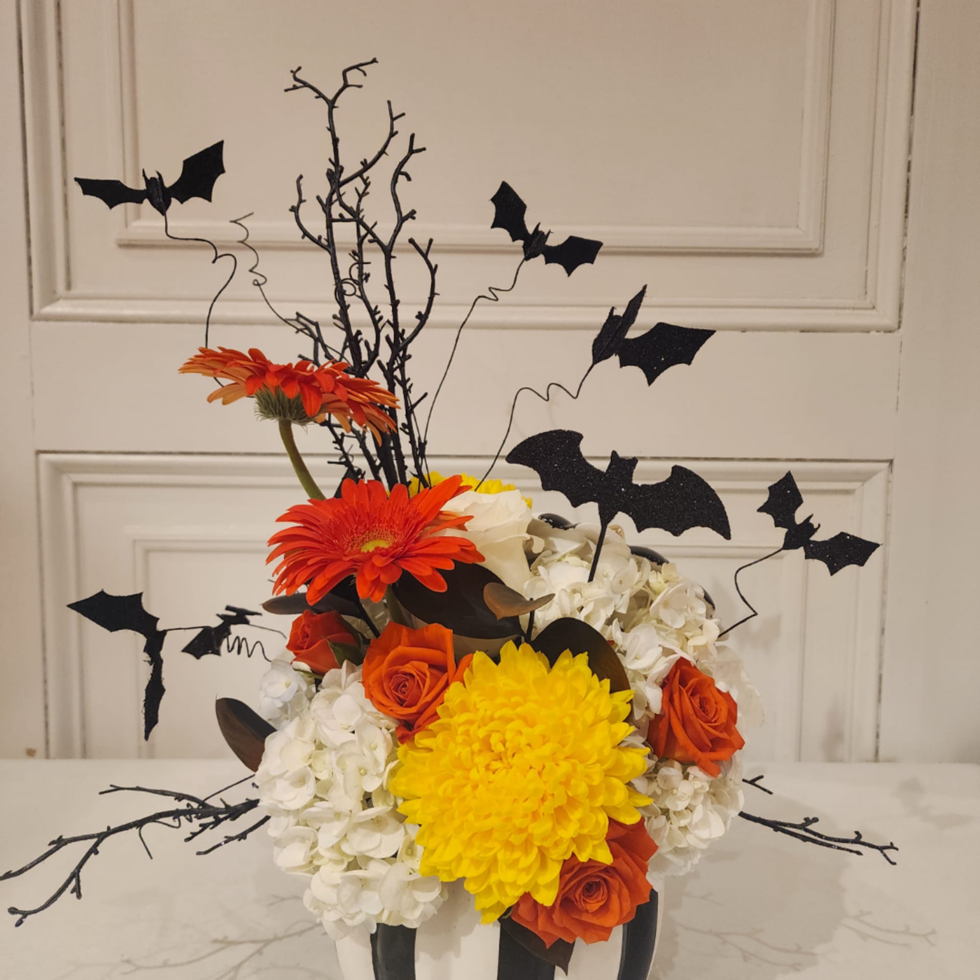 Halloween floral arrangement with orange and yellow blooms and bat picks