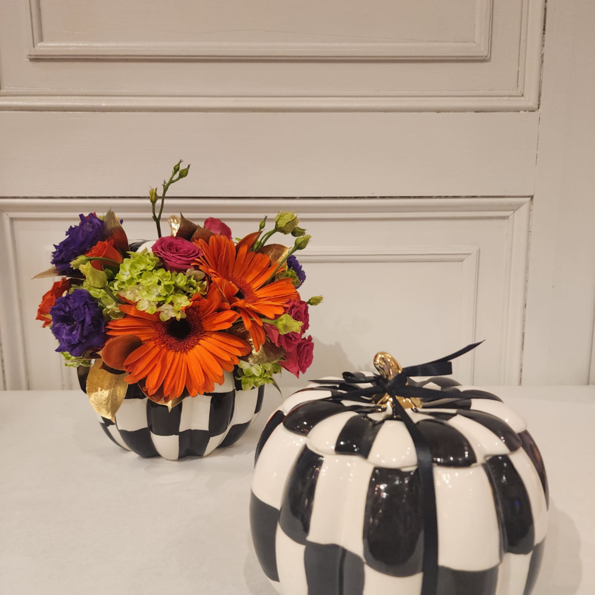 Orange gerbera bouquet in a black-and-white pumpkin vase with a matching lid