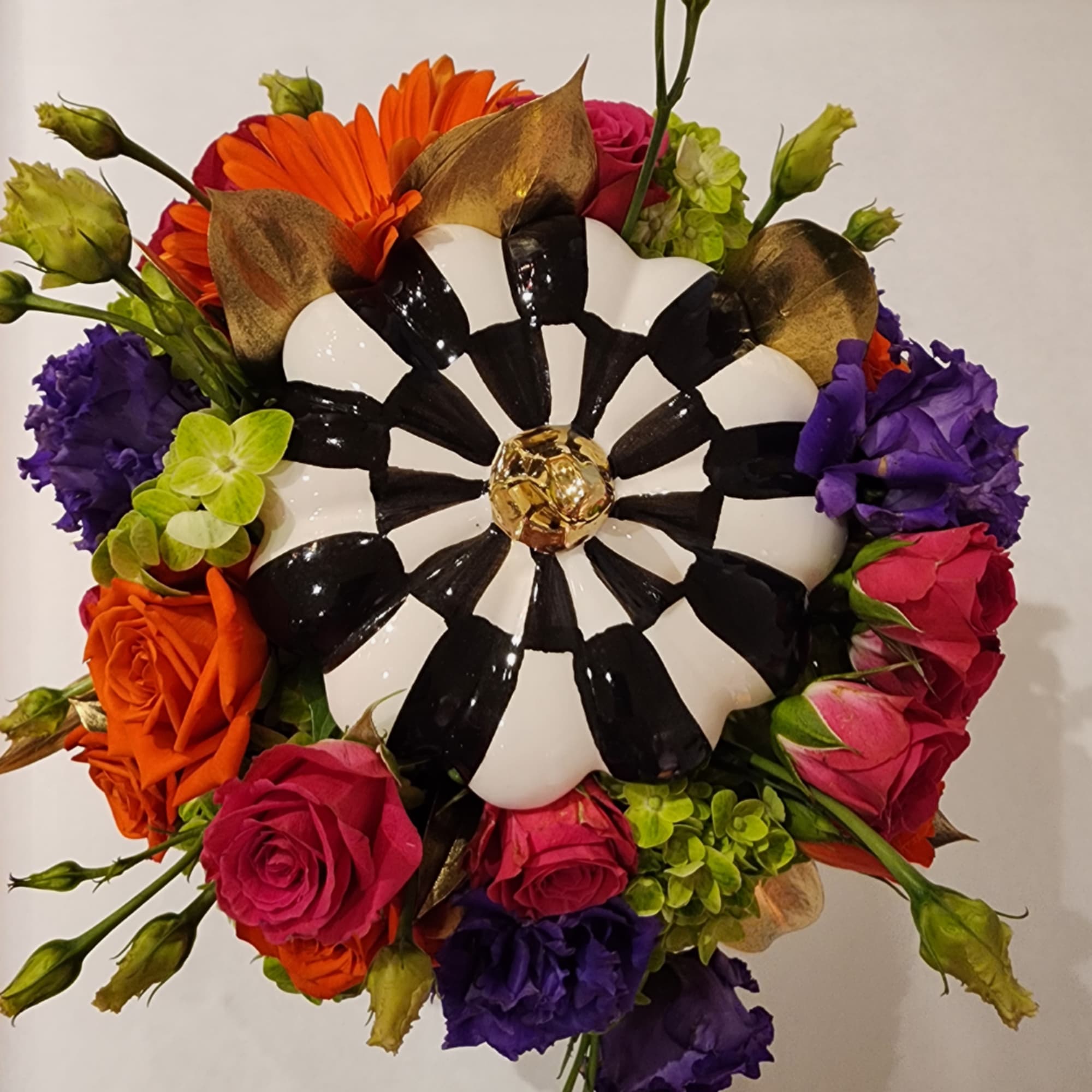 Colorful bouquet with roses, gerbera daisies, and a black-and-white decorative center