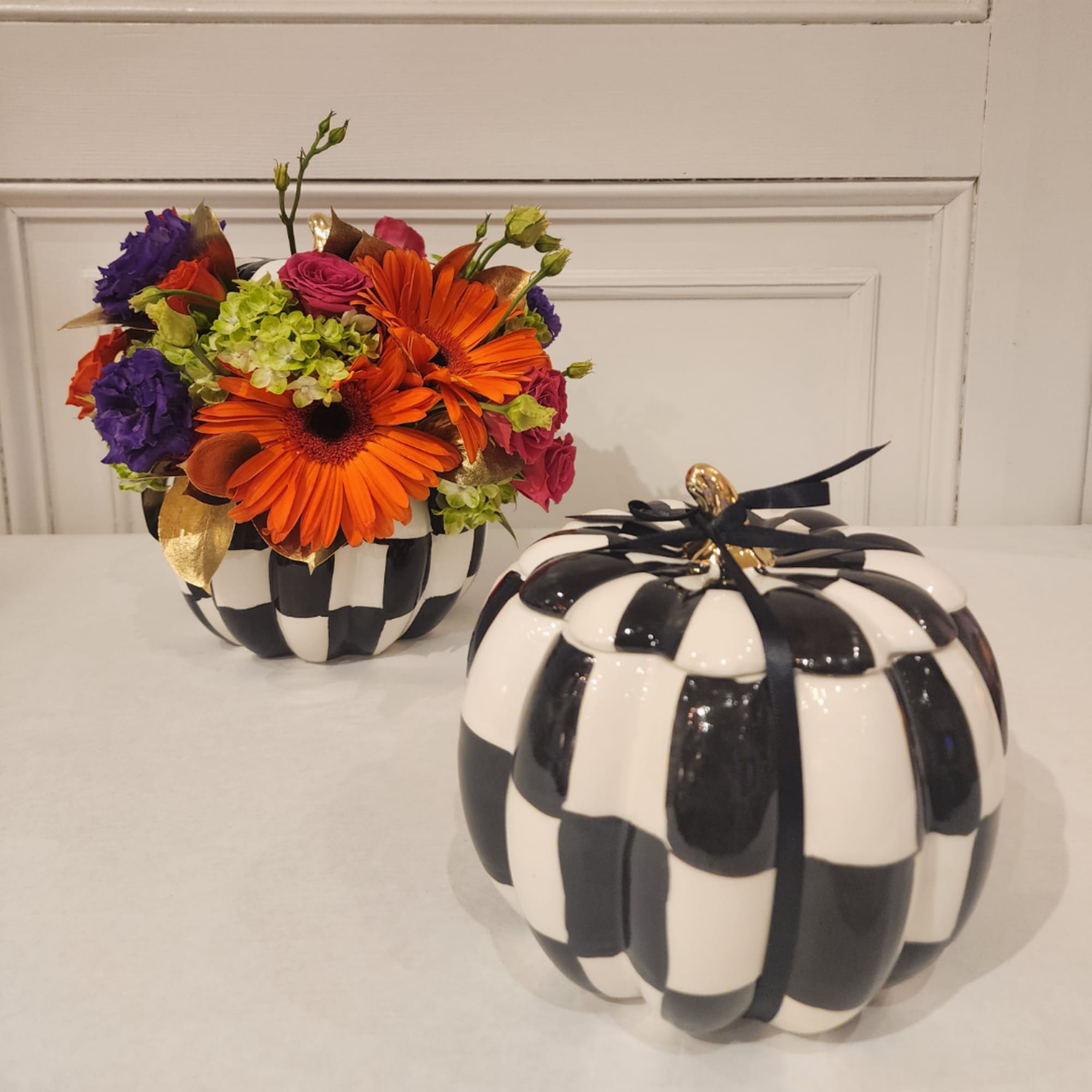 Bright mixed flower arrangement in a black-and-white pumpkin container