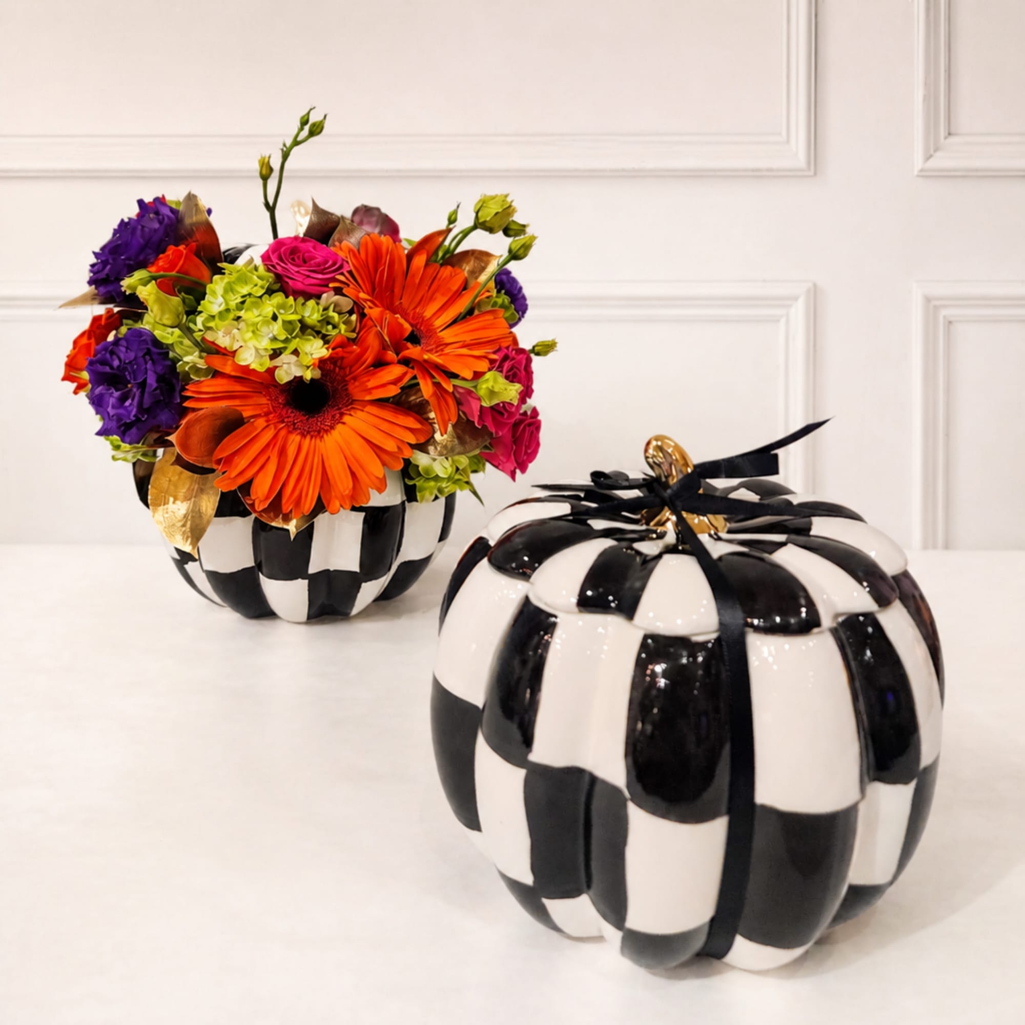Bright mixed flower arrangement in a black-and-white pumpkin container