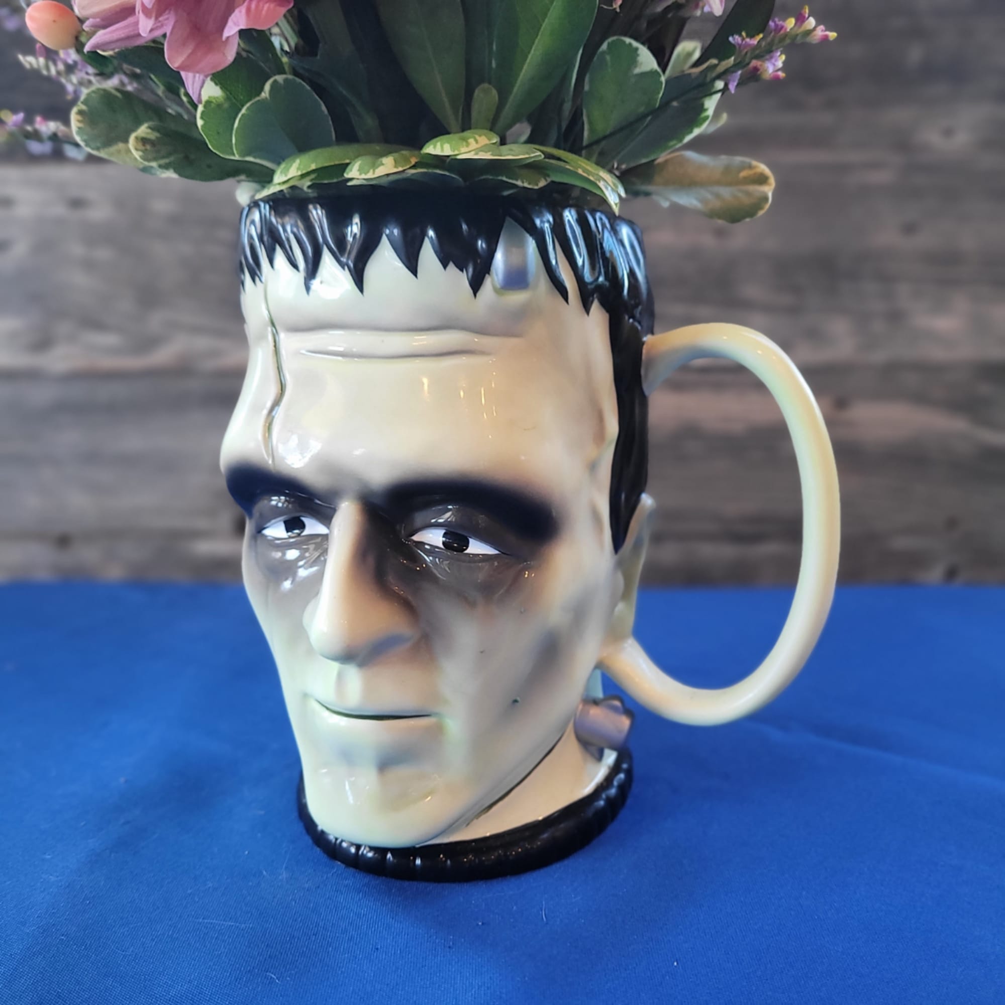 Frankenstein head mug holding pink flowers