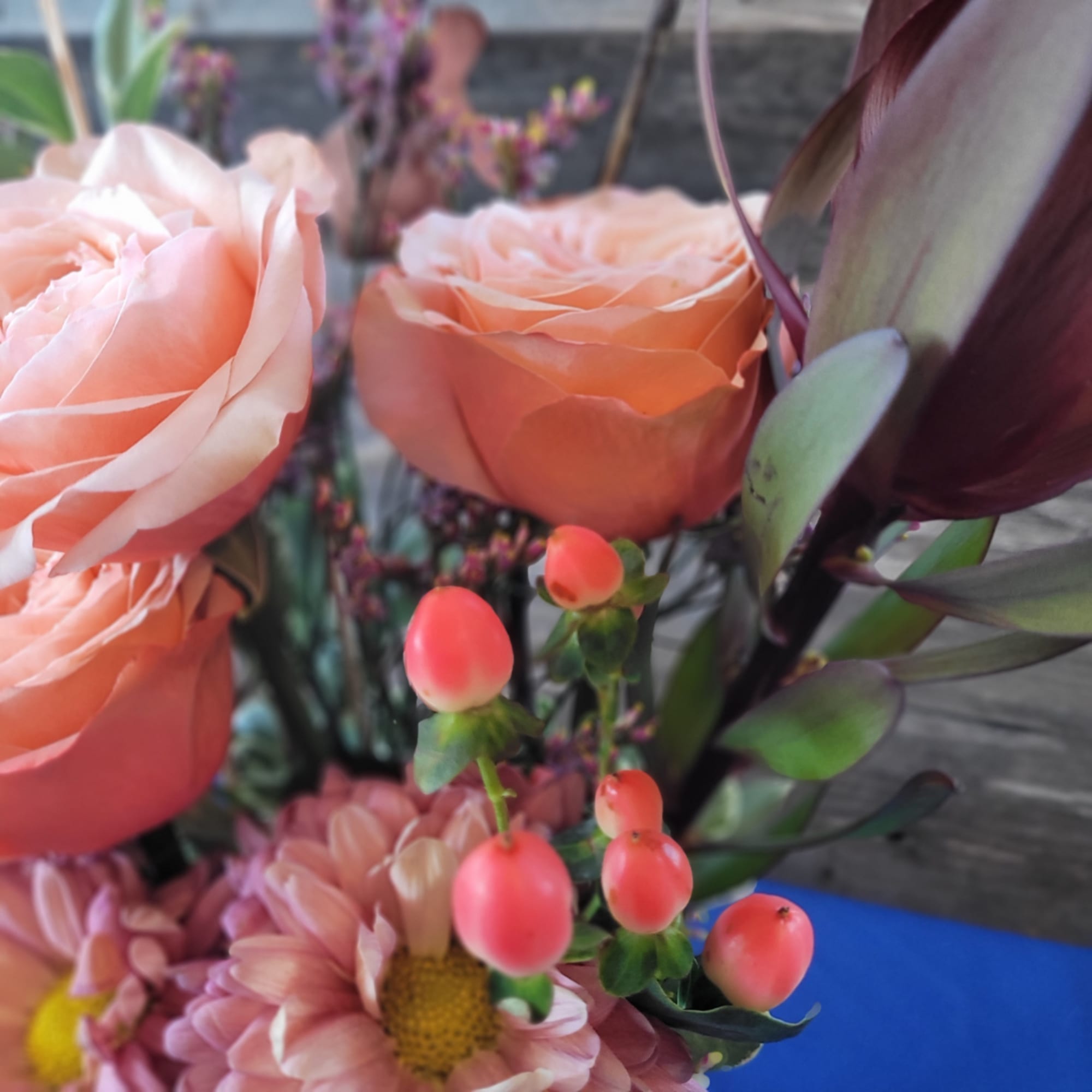Peach roses with pink daisies and berry-like accents in a bouquet