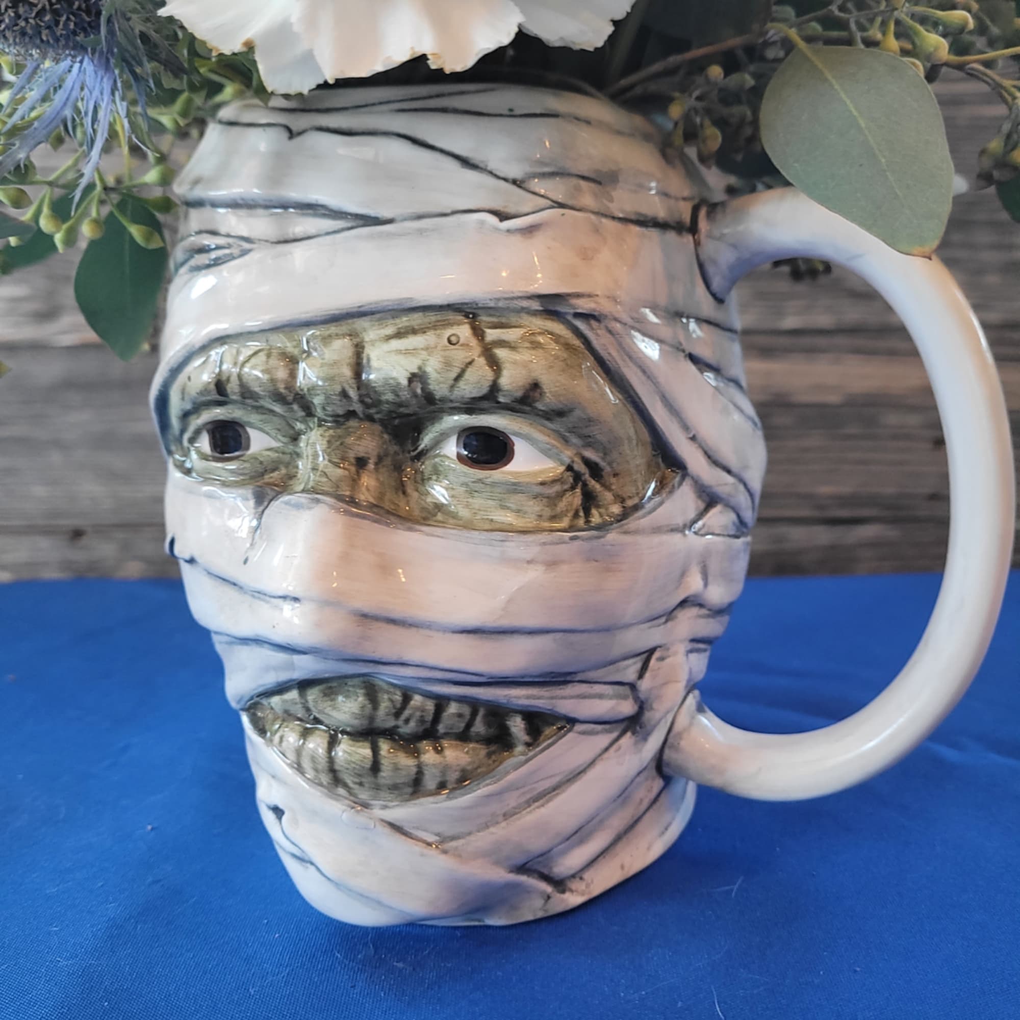 Ceramic mummy-face mug with flowers at the top