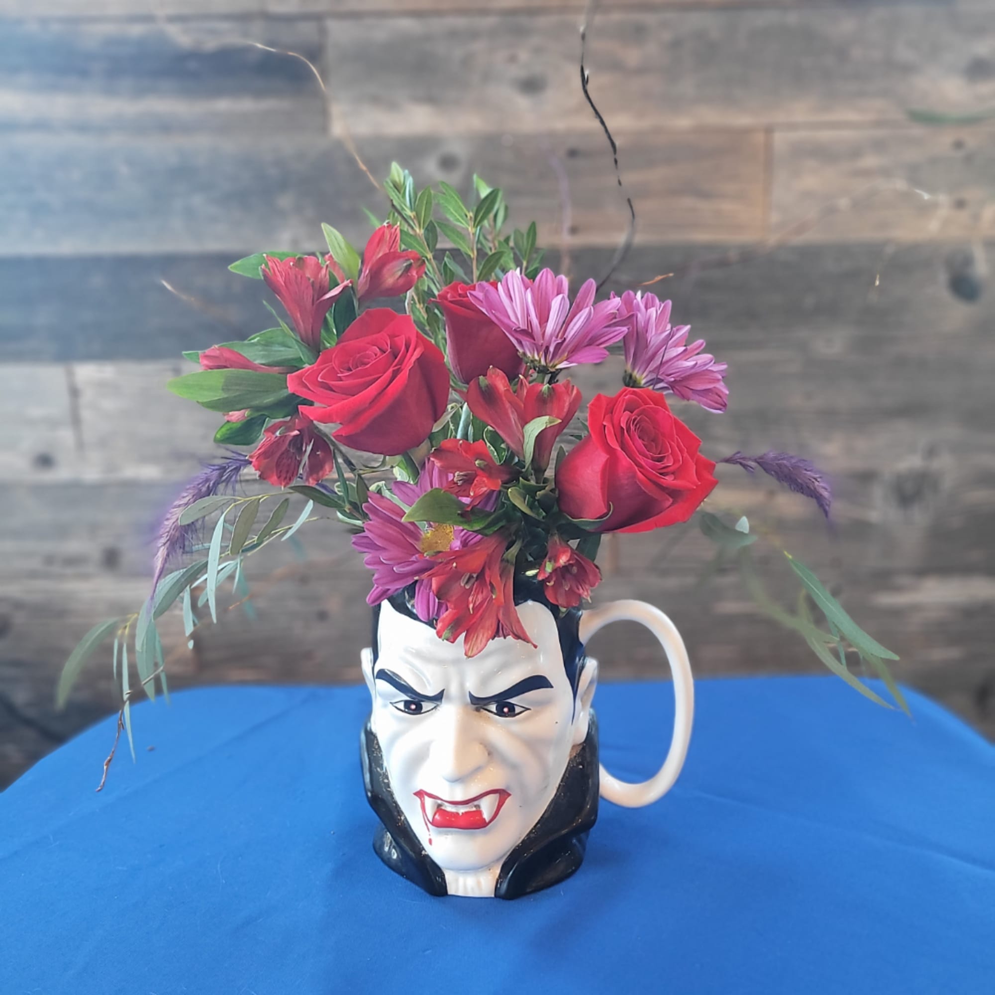 Red roses and pink daisies in a vampire face mug