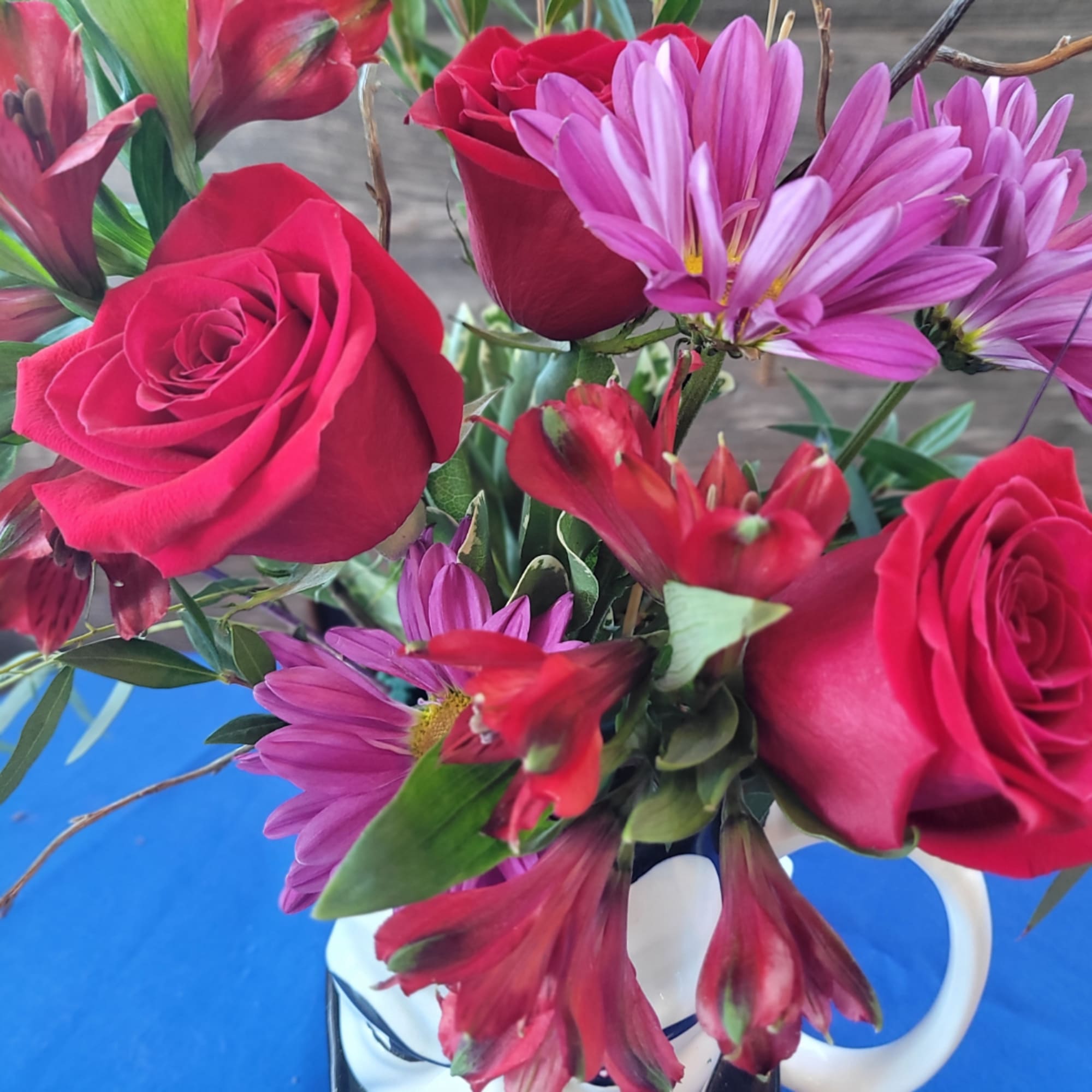 Bouquet of pink roses and purple daisies in a white mug