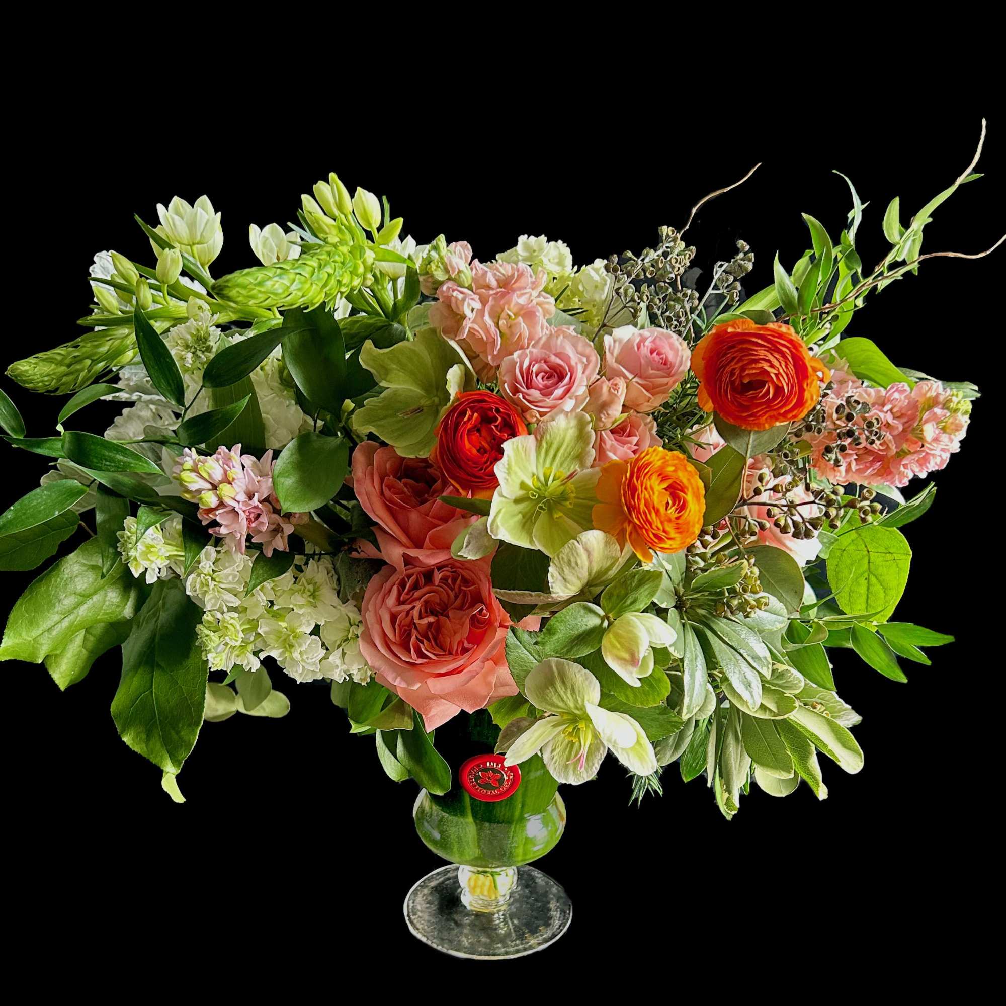 Mixed bouquet of pink, orange, and white flowers in a glass vase