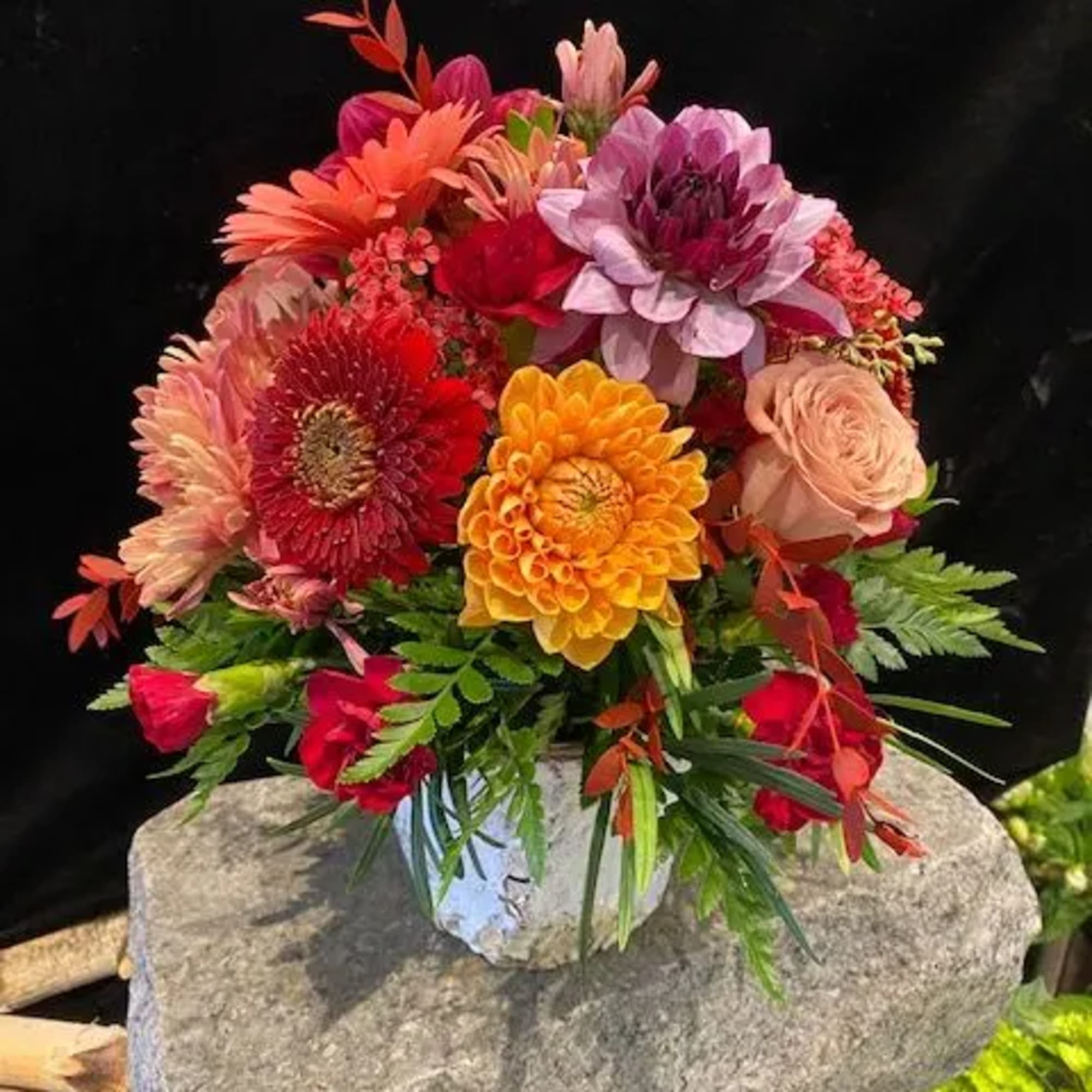 Colorful mixed bouquet in a white vase with orange, pink, red, and purple blooms