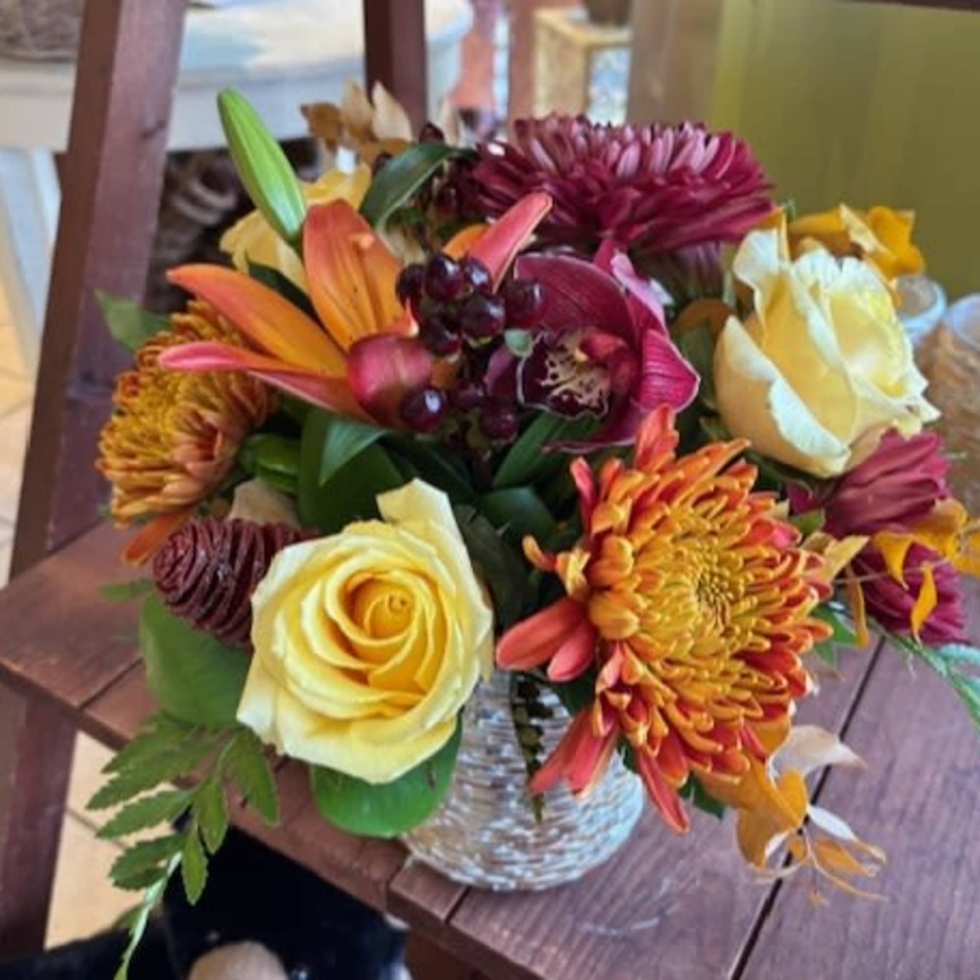 Mixed bouquet of roses, lilies, and chrysanthemums in a glass vase