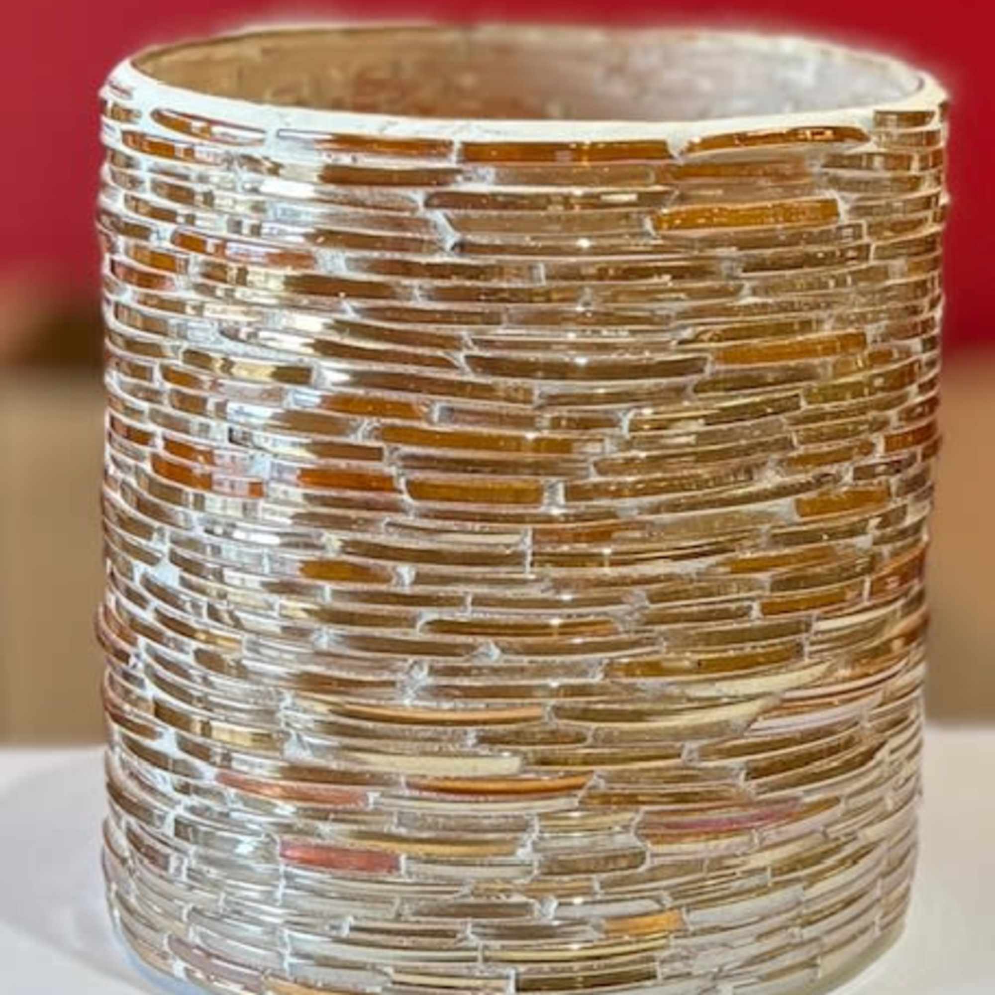 Textured gold glass votive holder on a white surface