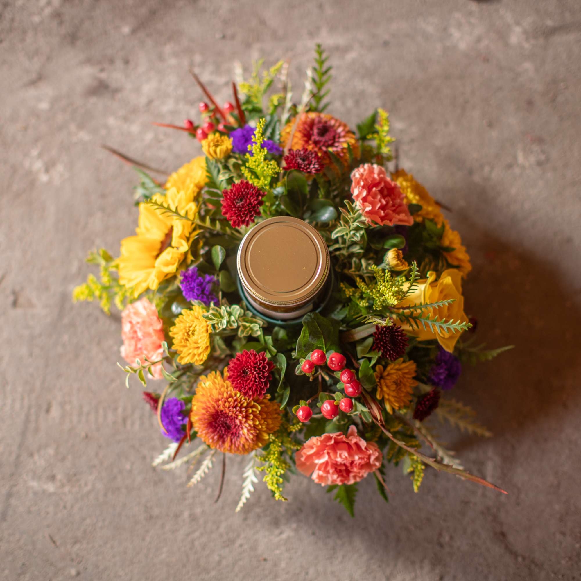 Round floral arrangement with a candle jar in the center