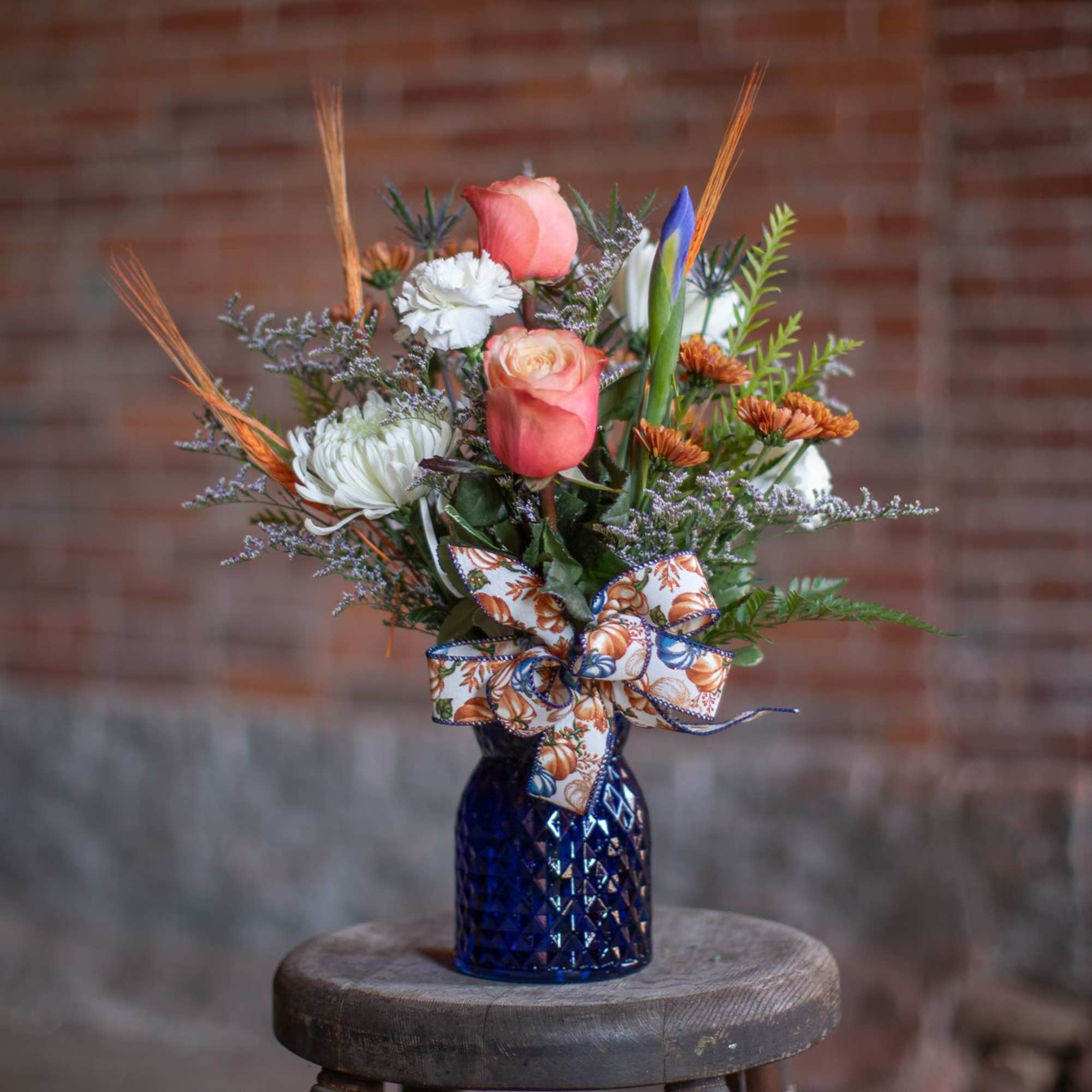 Pink and white mixed bouquet in a blue vase with a decorative bow