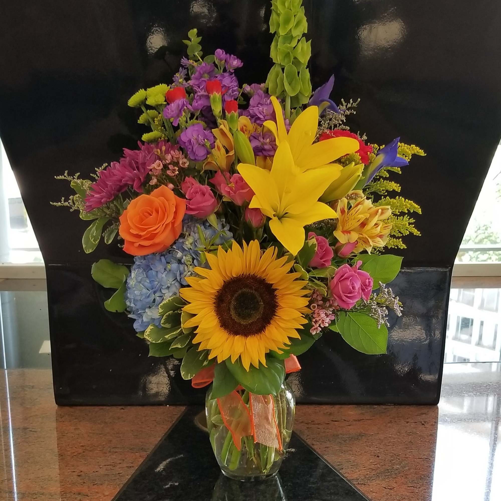 Colorful mixed bouquet in a glass vase with a sunflower and yellow lily