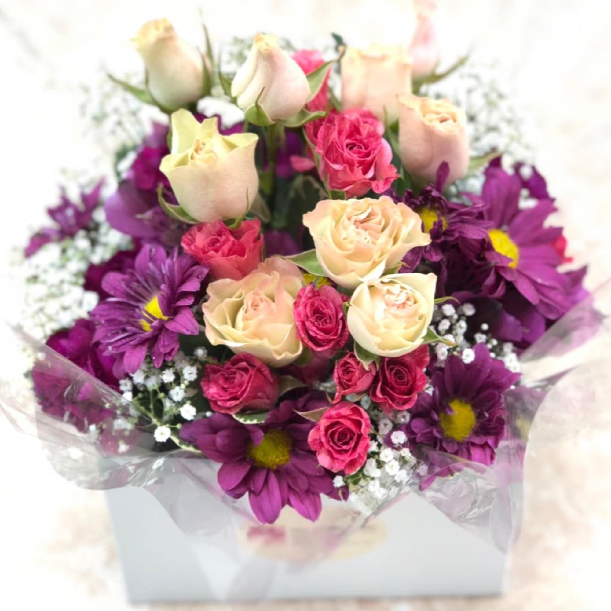 Bouquet of cream and pink roses with purple daisies