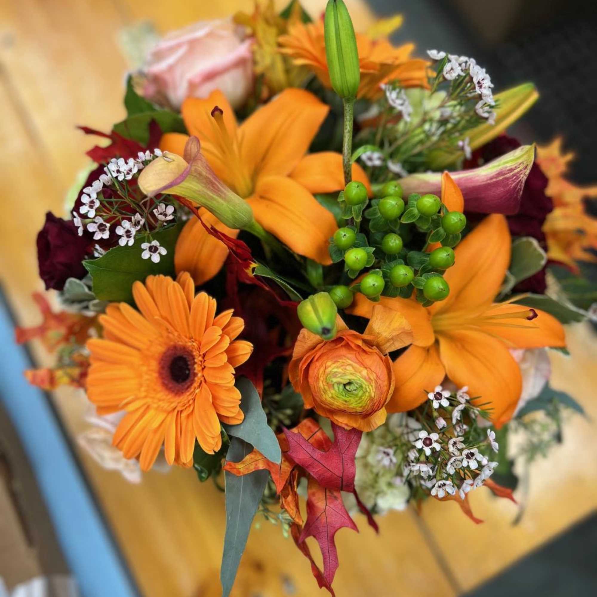 Orange and burgundy mixed bouquet with lilies, gerbera daisies, and calla lilies