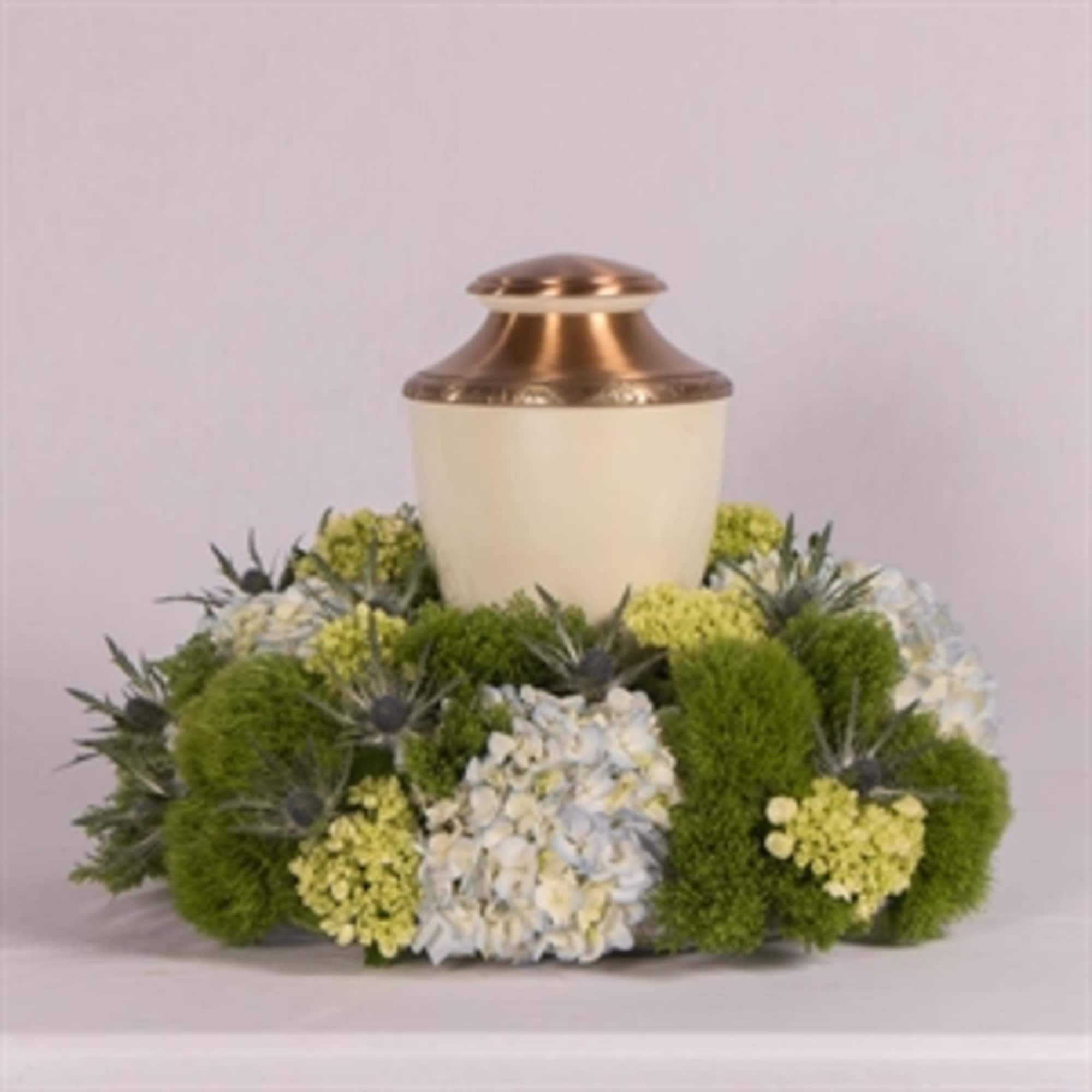 Funeral urn surrounded by green and white flowers