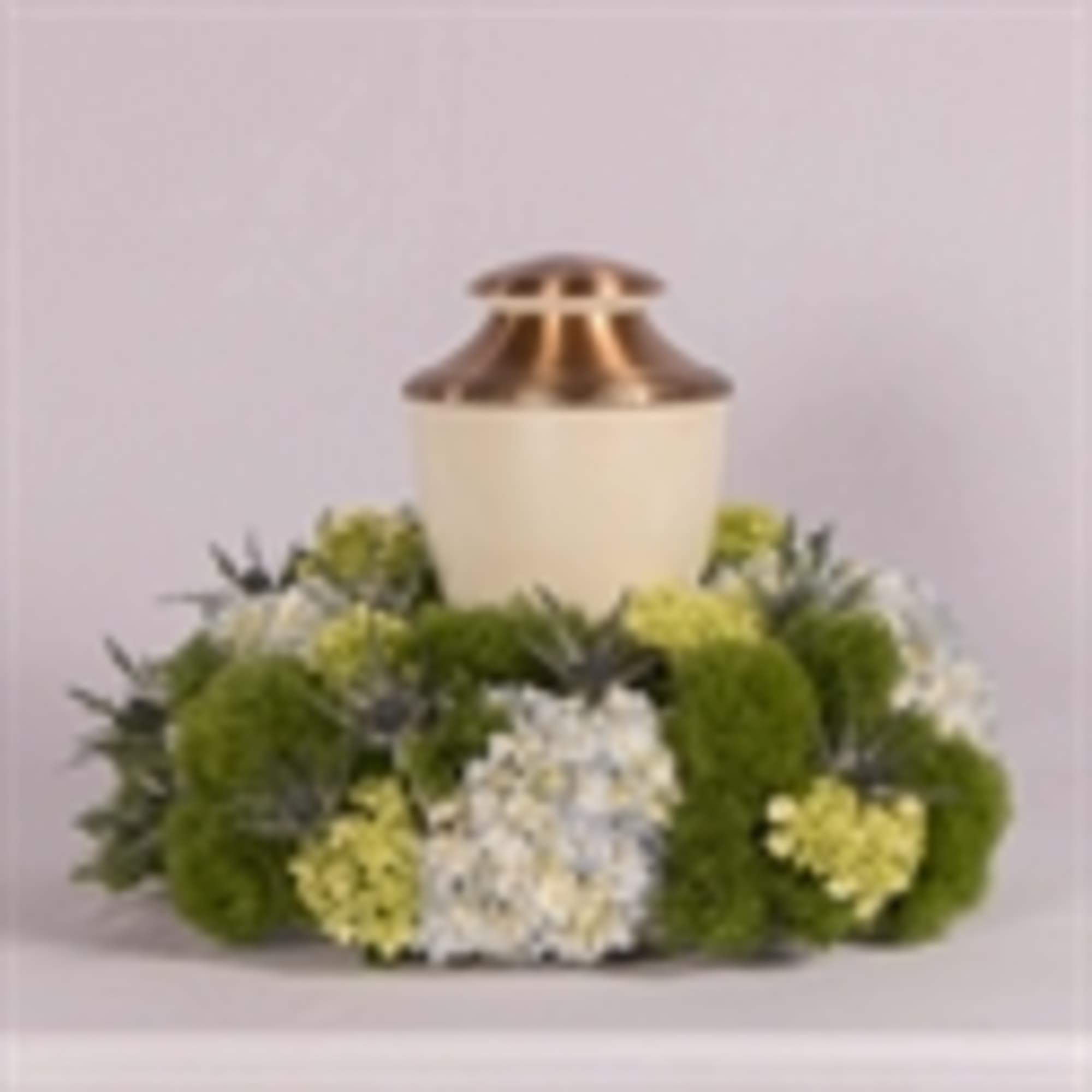 White urn surrounded by green and white flowers