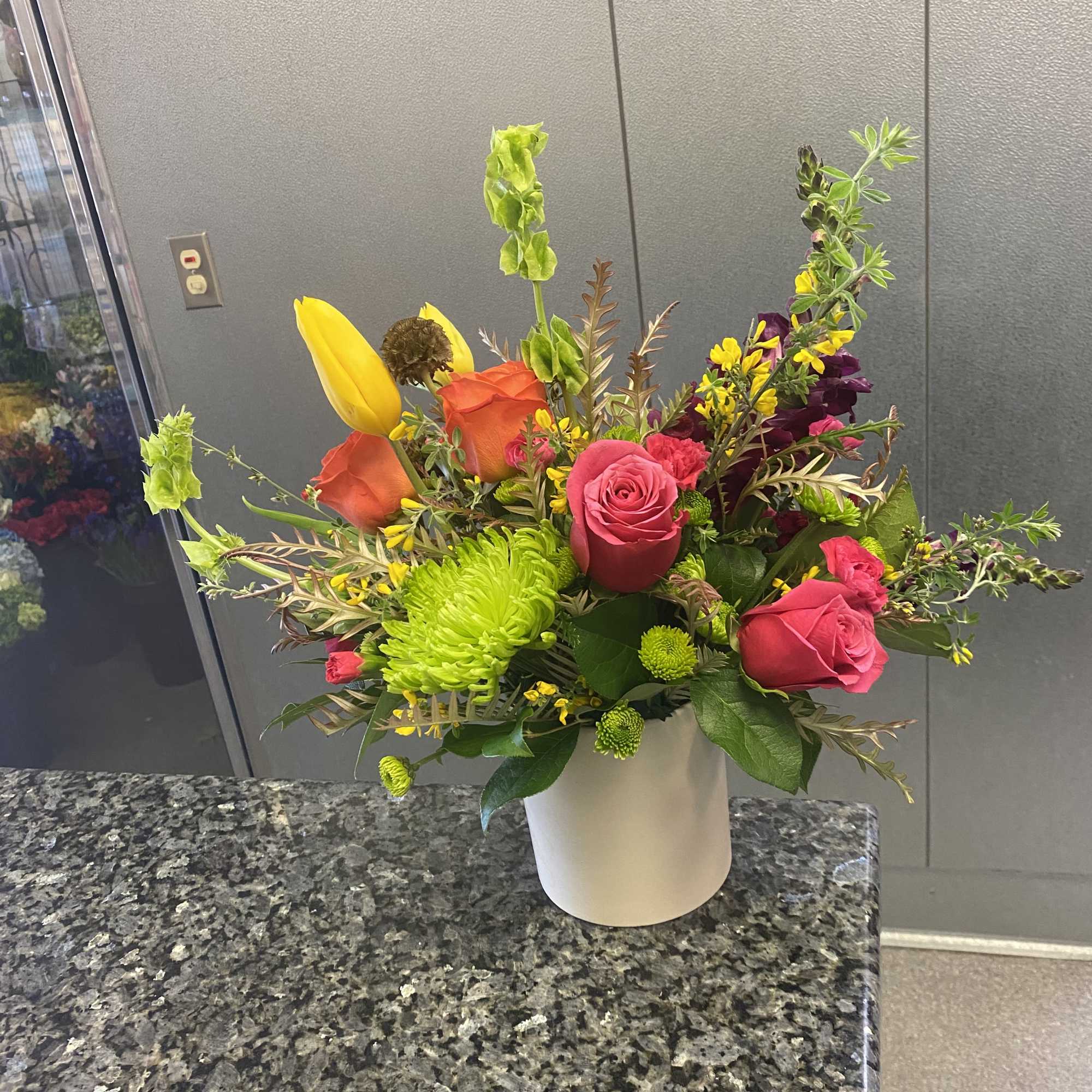 Mixed bouquet of roses, tulips, and chrysanthemums in a white vase