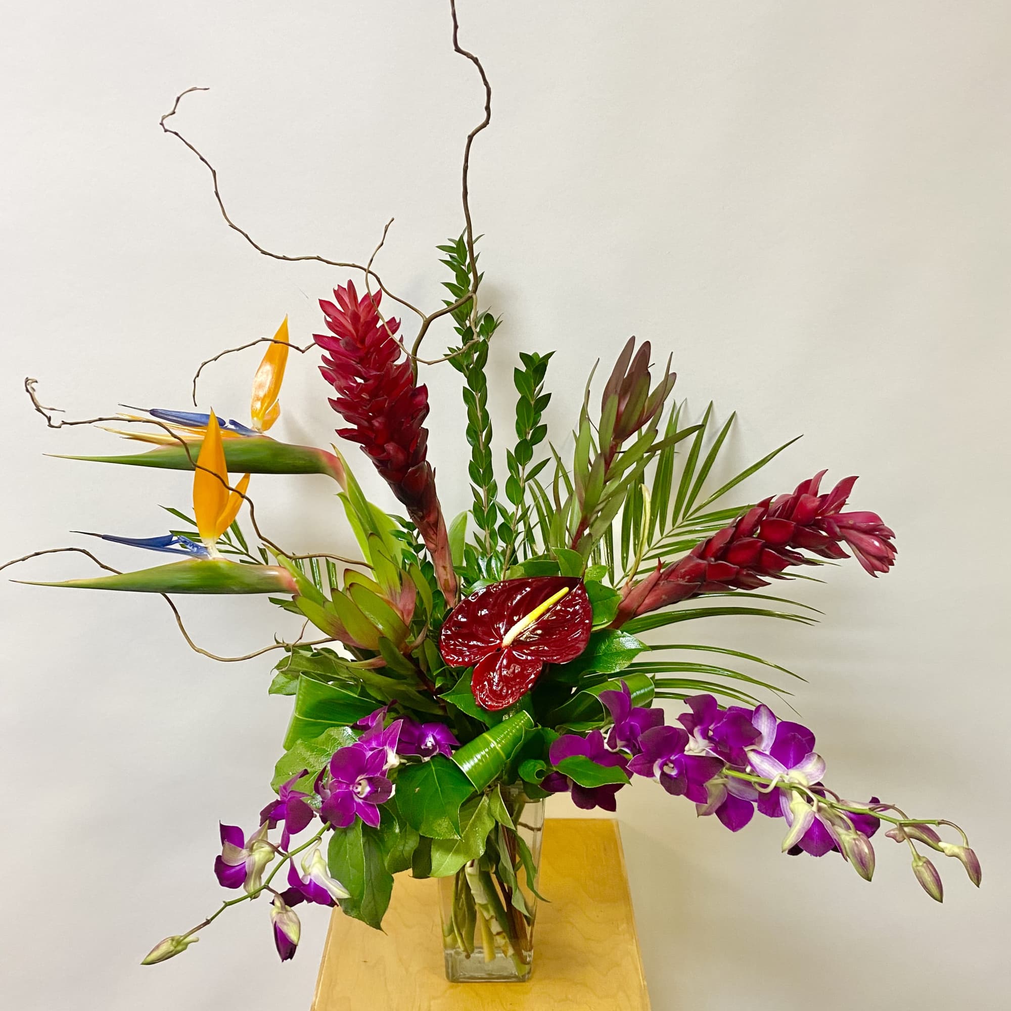 Tropical arrangement with purple orchids in a glass vase