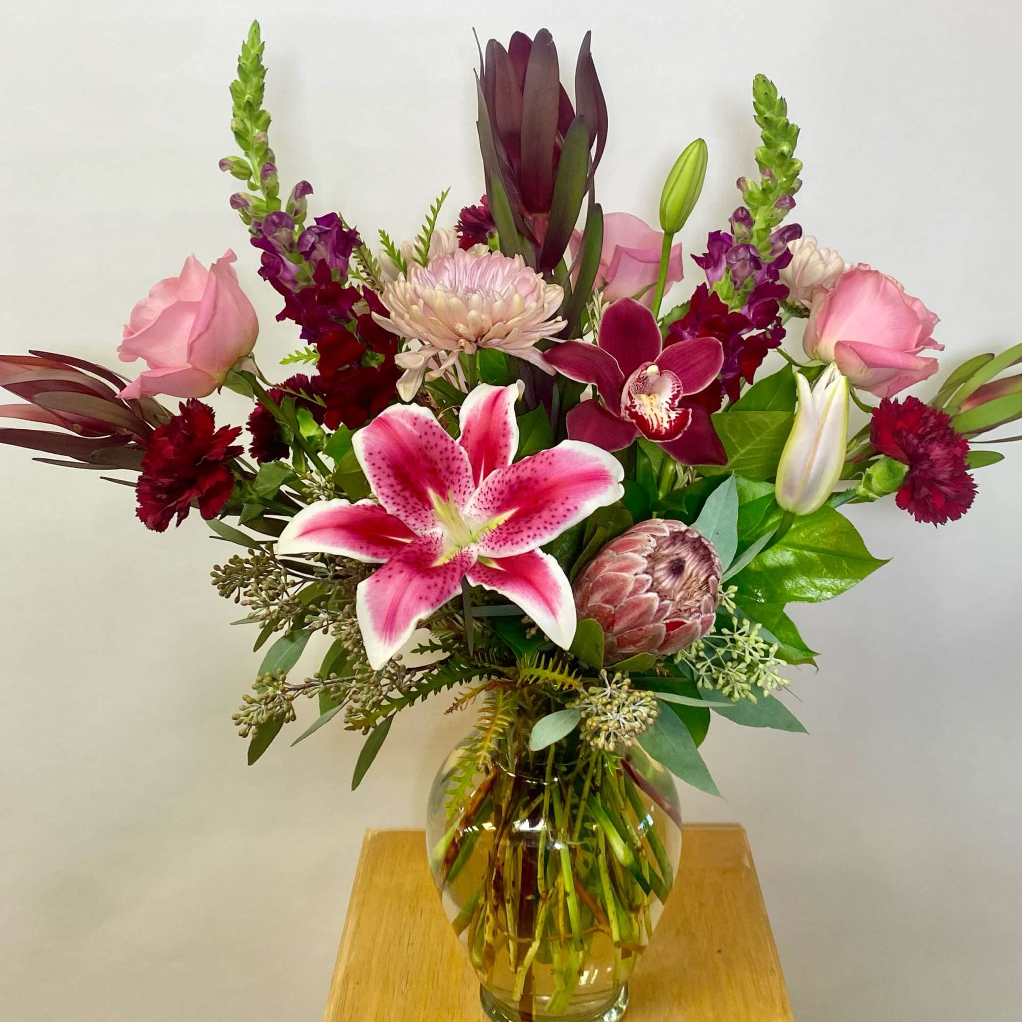 Mixed pink and burgundy floral arrangement in a clear glass vase