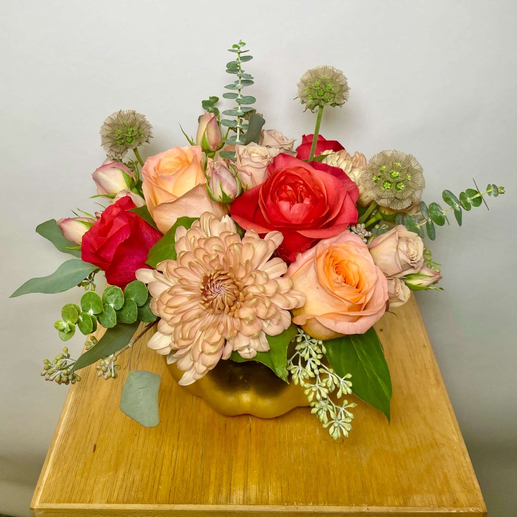 Mixed bouquet of roses and a large chrysanthemum in a gold vase