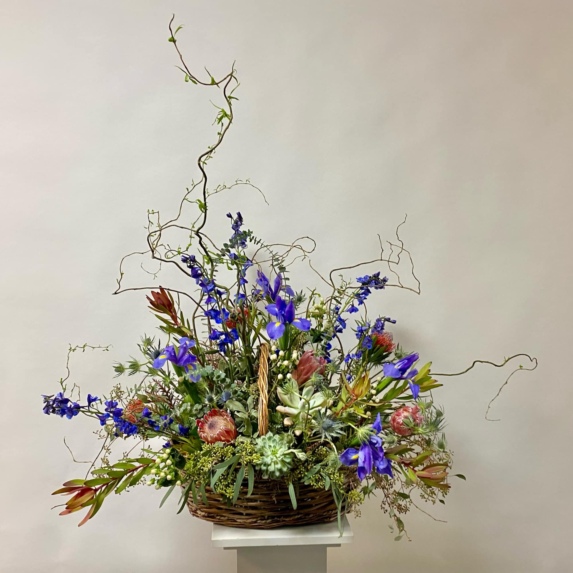 Large basket arrangement with blue flowers and succulents