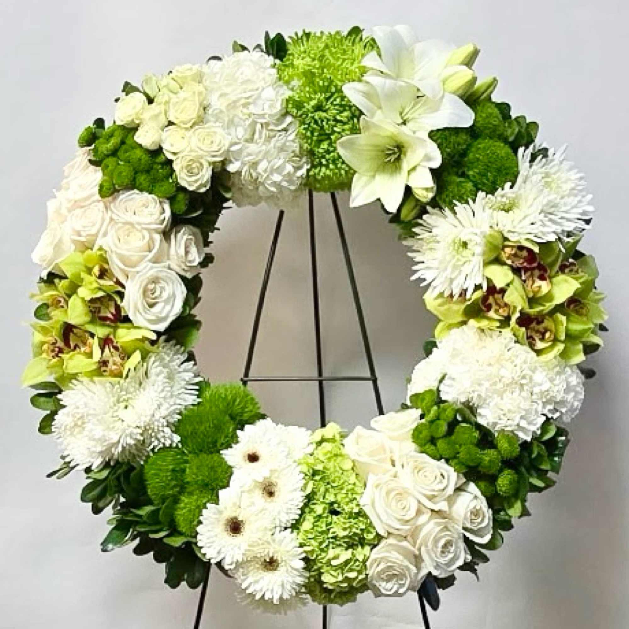 Large white and green floral wreath on a stand